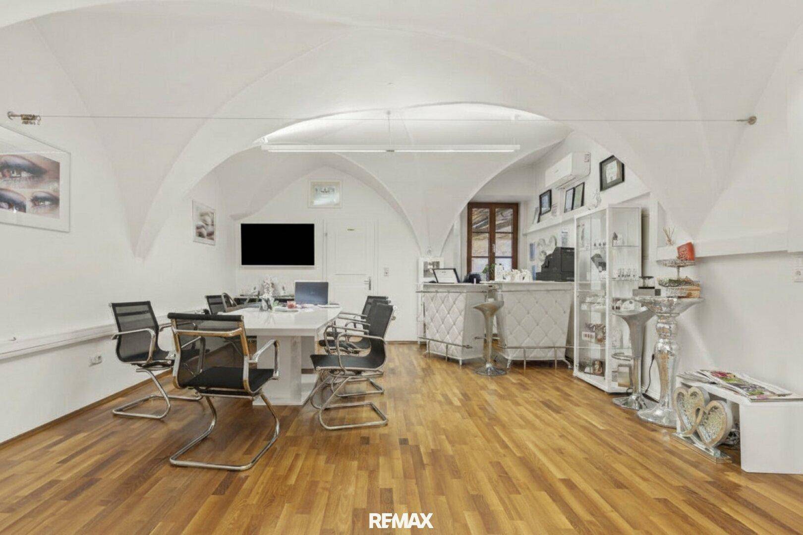 Modern eingerichtetes Büro mit Holzboden, Gewölbedecke und Besprechungstisch.