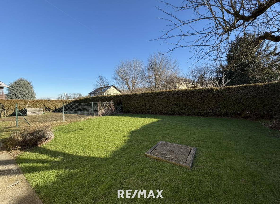 Gepflegter Gartenbereich mit Rasen und Hecke unter blauem Himmel, bereit zur Nutzung.
