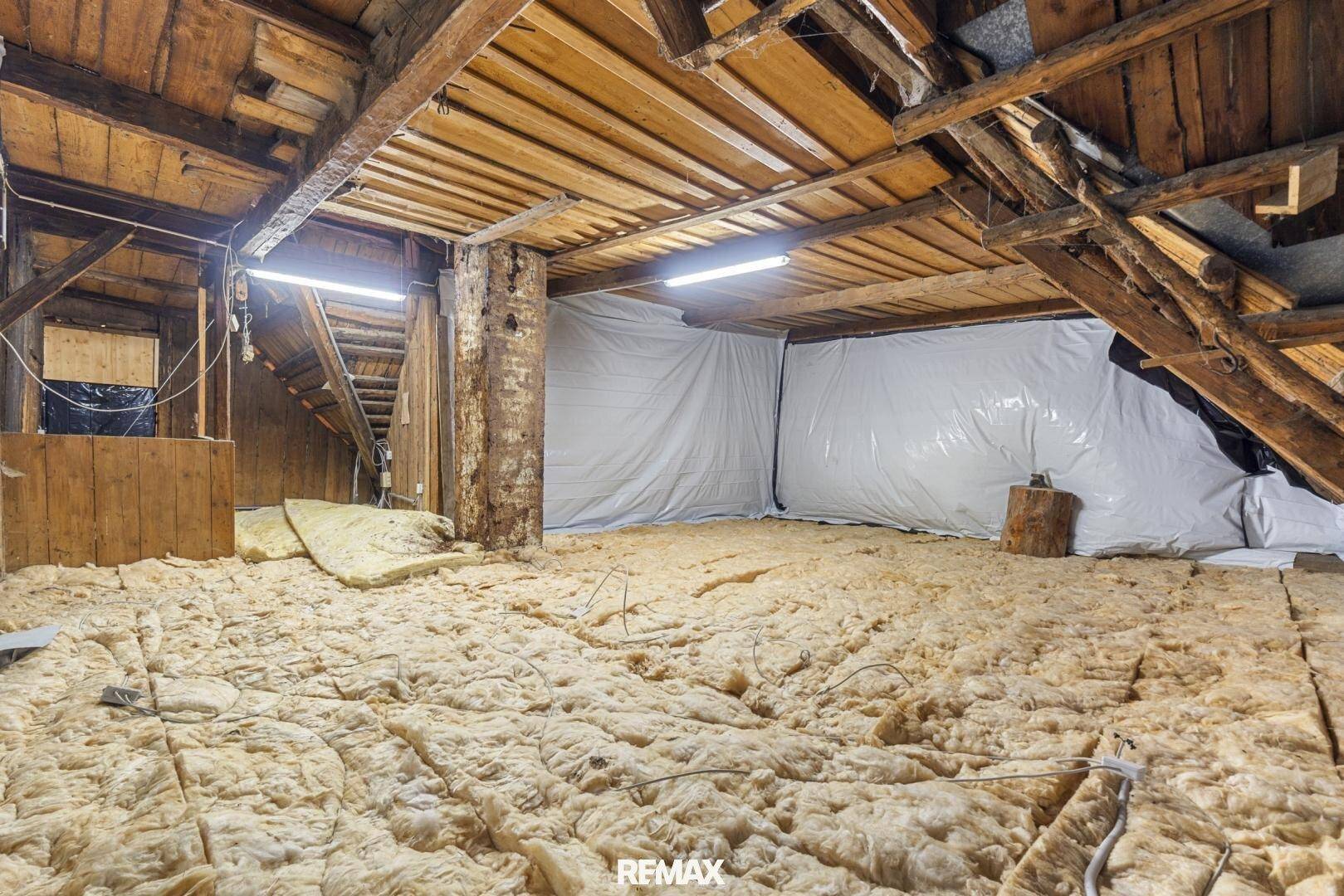 Großer Dachbodenbereich mit Holzbalken und Isolierung, ideal für Ausbau oder Lagerung.