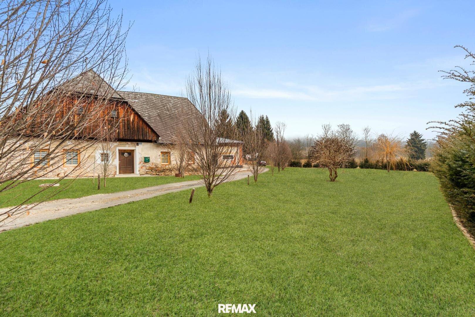 Weitläufiges Grundstück mit altem Bauernhaus und Blick auf die umliegende Landschaft.