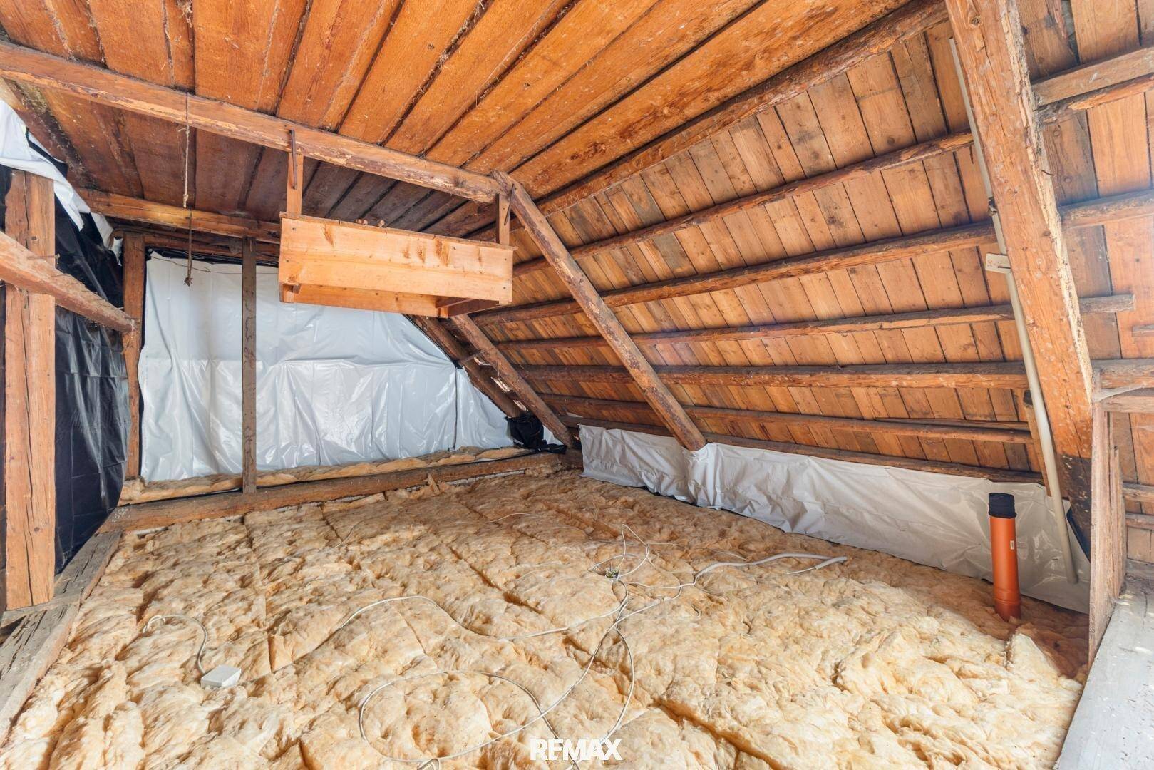 Dachboden mit sichtbaren Holzbalken und Isolierung, bietet Potenzial für zukünftige Nutzung.