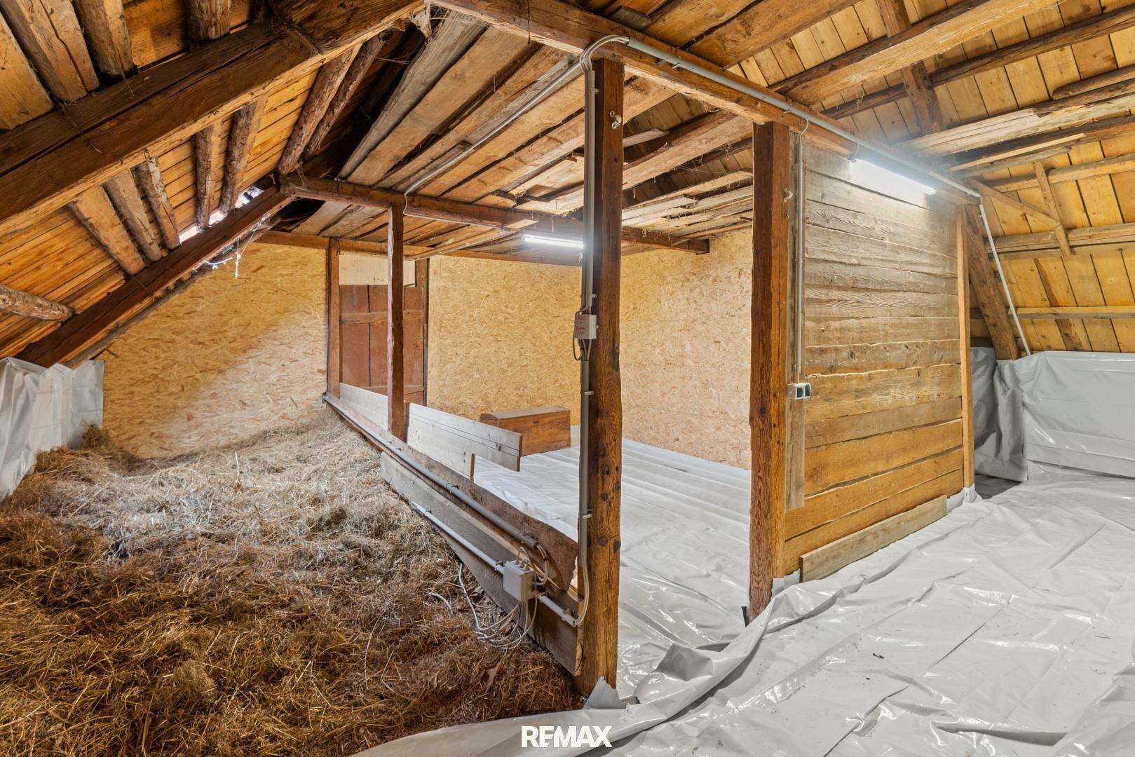 Geräumiger Dachboden mit Holzbalken und Stroh, bietet viel Stauraum oder Ausbaupotenzial.