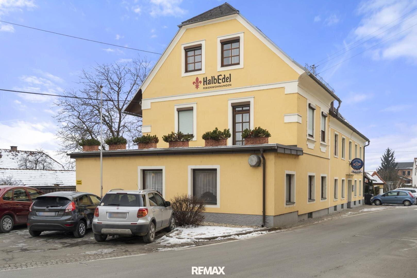 Gelbes Gebäude mit traditioneller Architektur, Parkplätzen und verschneiter Umgebung.