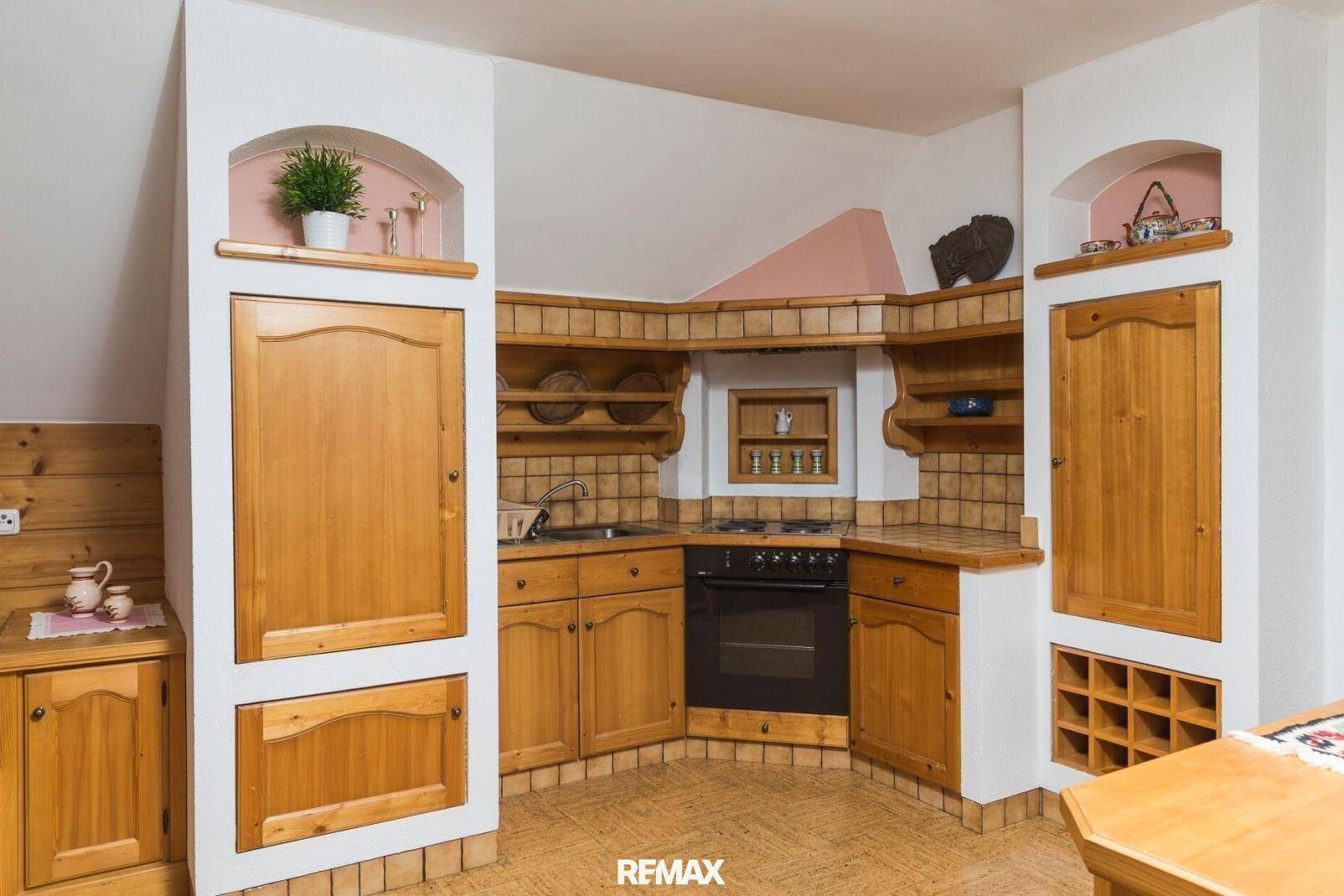 Rustikale Küche im Dachgeschoss mit Holzeinbauten, integriertem Backofen und gefliesten Arbeitsflächen.