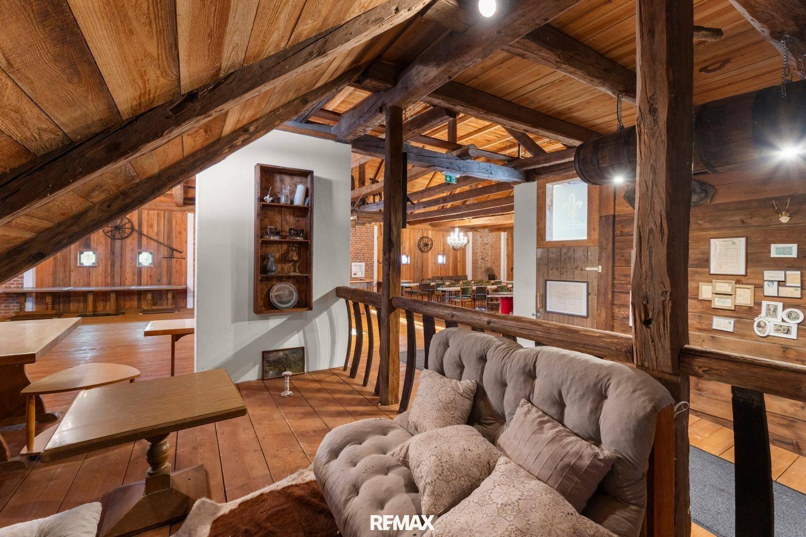 Mezzanine-Bereich im Veranstaltungssaal mit gemütlicher Sitzecke und Blick auf den Hauptraum.