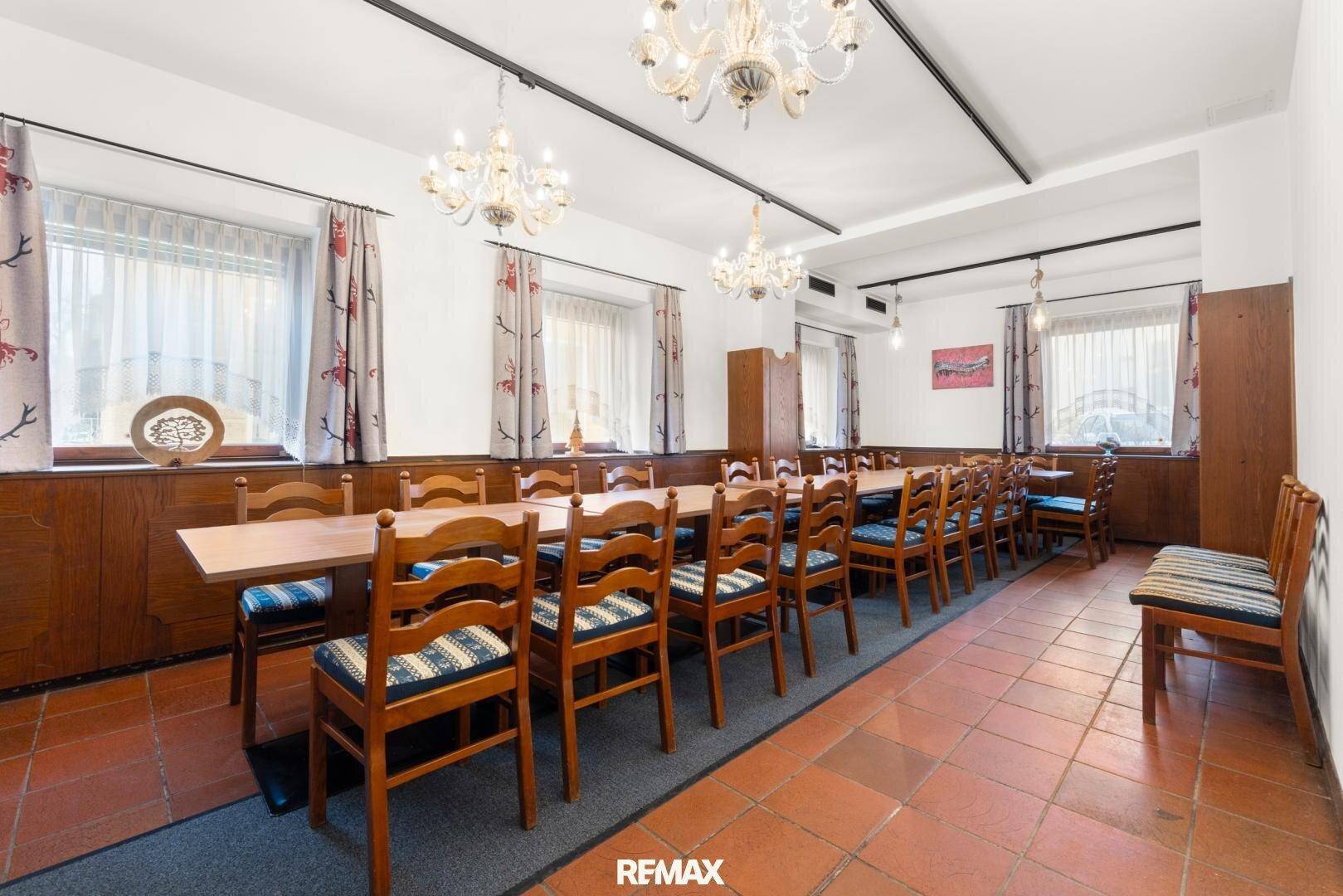 Großer Speisesaal mit Holzboden, Kronleuchtern und langen Tischen für Veranstaltungen.