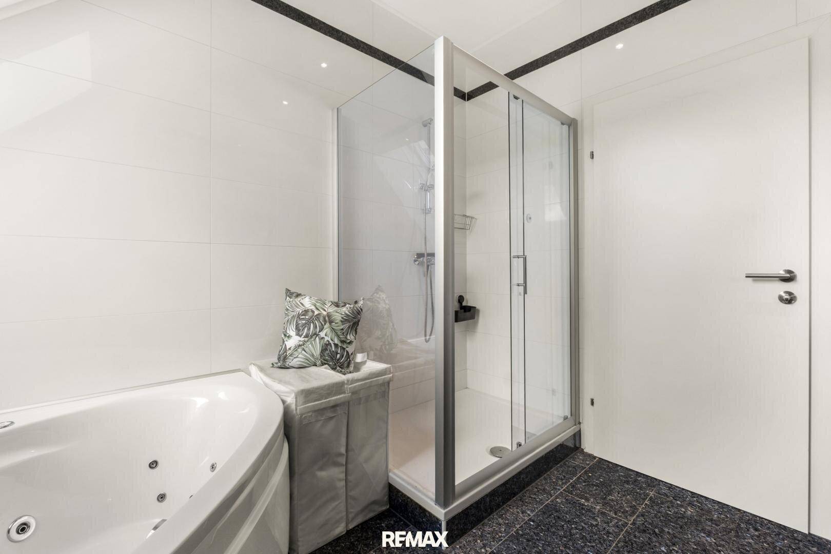 Modernes Badezimmer mit Eckbadewanne und separater Duschkabine, hell gefliest.