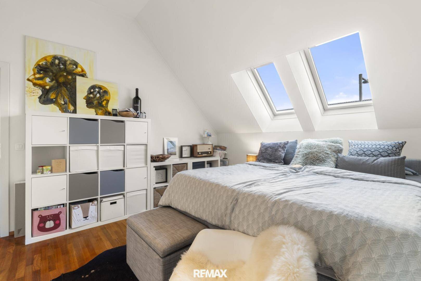 Gemütliches Schlafzimmer mit Doppelbett, Stauraum und viel Tageslicht durch Dachfenster.