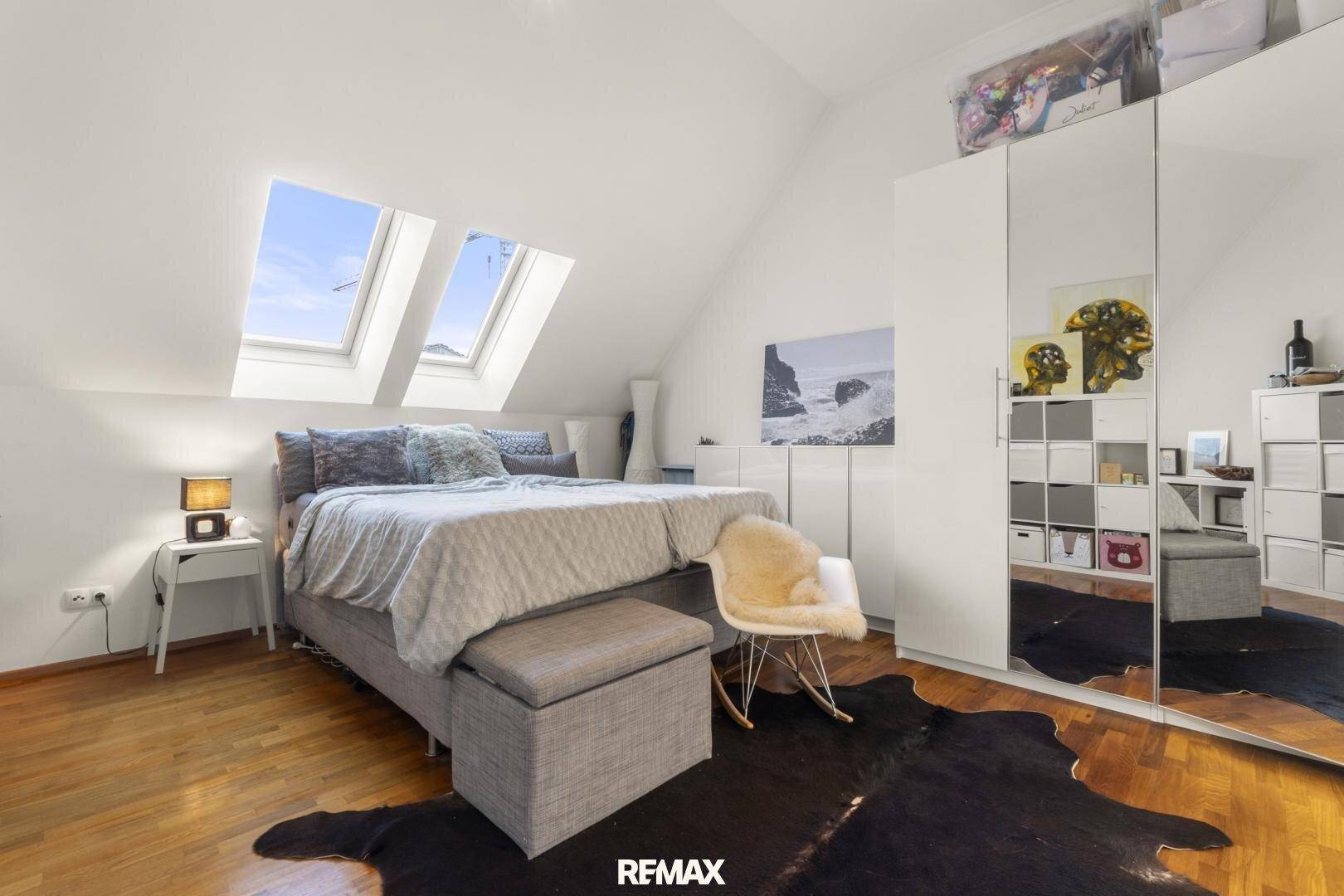 Helles Schlafzimmer im Dachgeschoss mit Doppelbett, Spiegelschrank und Dachfenstern.
