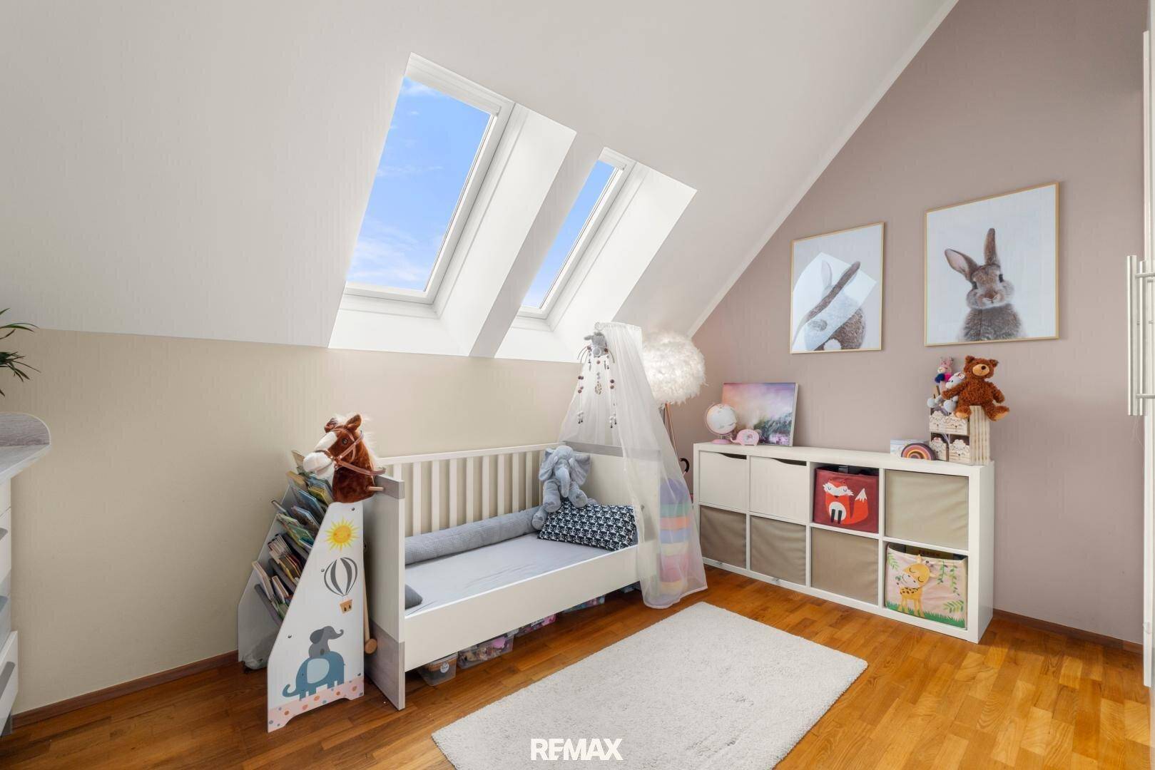 Kinderzimmer im Dachgeschoss mit Babybett, Stauraum und hellen Dachfenstern.