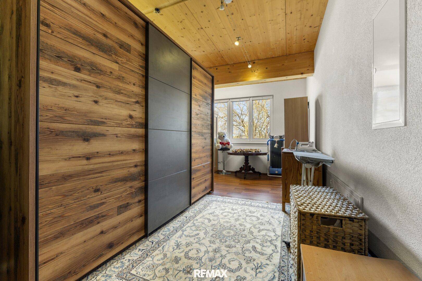 Schlafzimmer mit Holzboden, Einbauschränken und Fenster mit Blick ins Grüne.