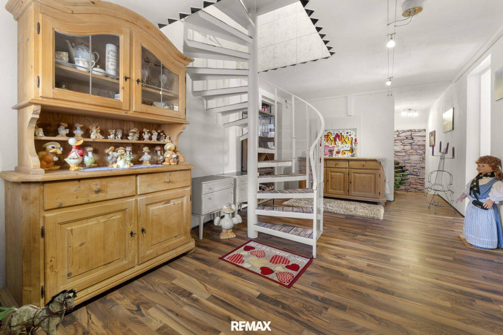 Flur mit Wendeltreppe, Holzboden und rustikalem Holzschrank.