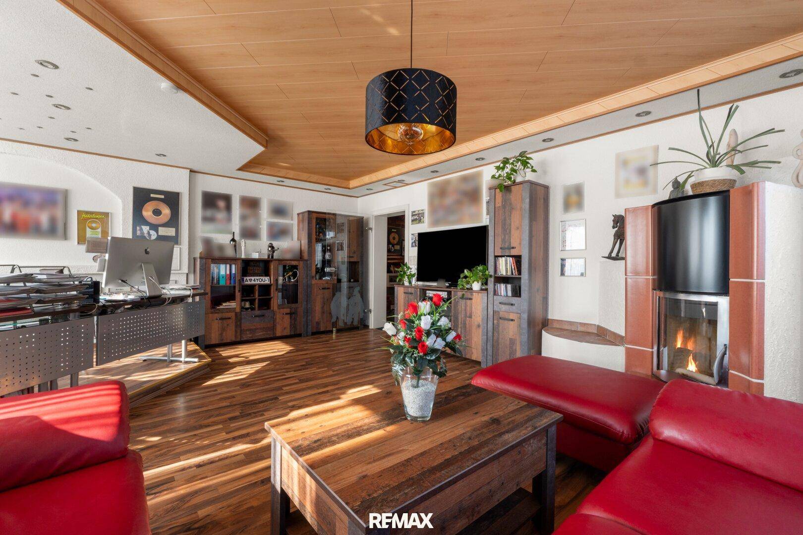 Gemütliches Wohnzimmer mit Kaminofen, Holzboden und integriertem Arbeitsbereich.