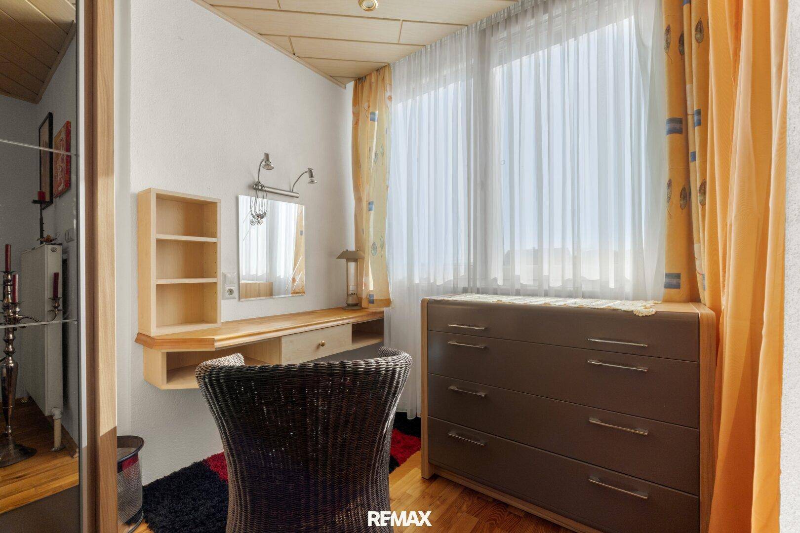 Kleiner Ankleidebereich oder Schlafzimmerecke mit Schminktisch und Kommode am Fenster.