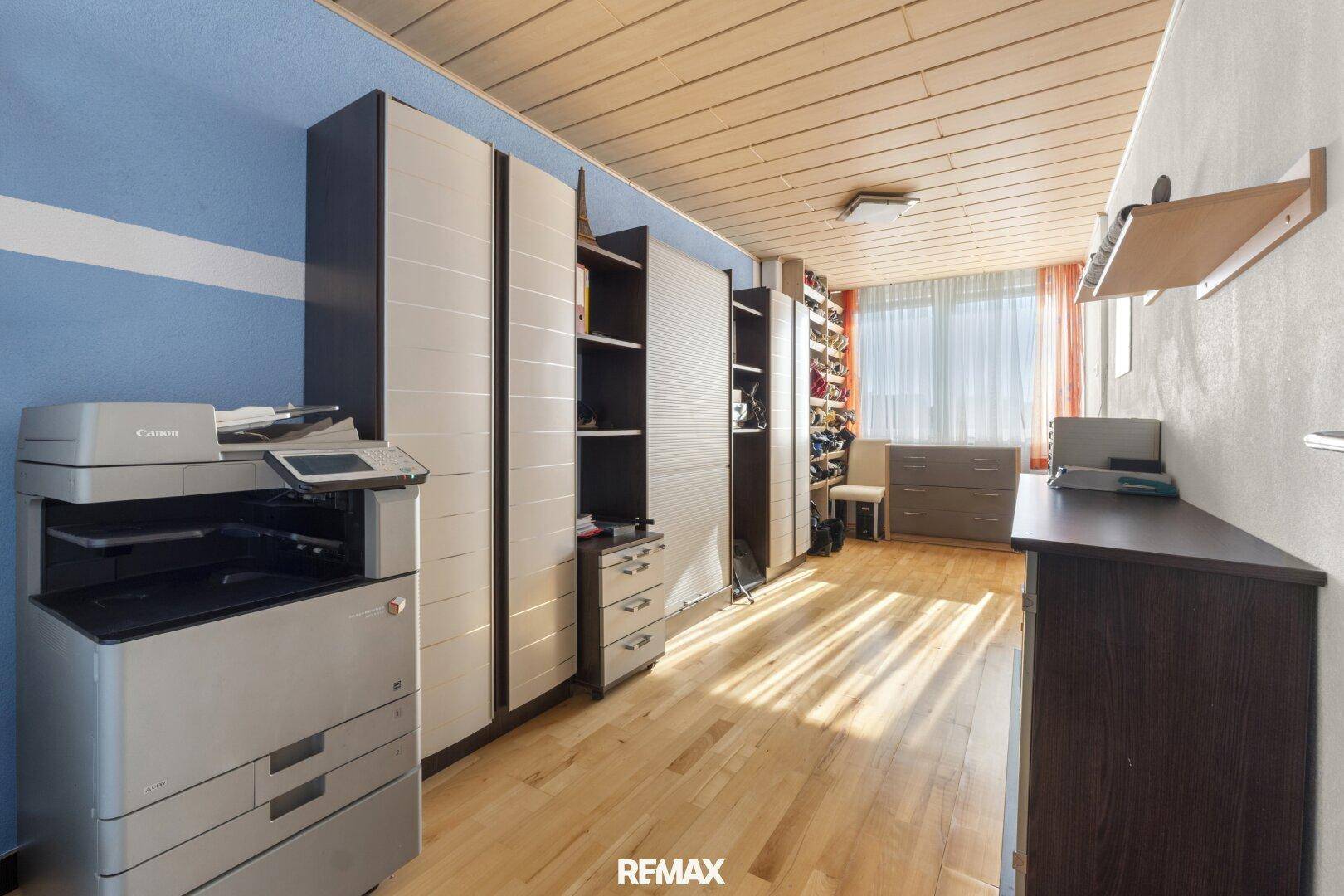 Helles Arbeitszimmer mit Holzdecke, Einbauschränken und Holzboden.