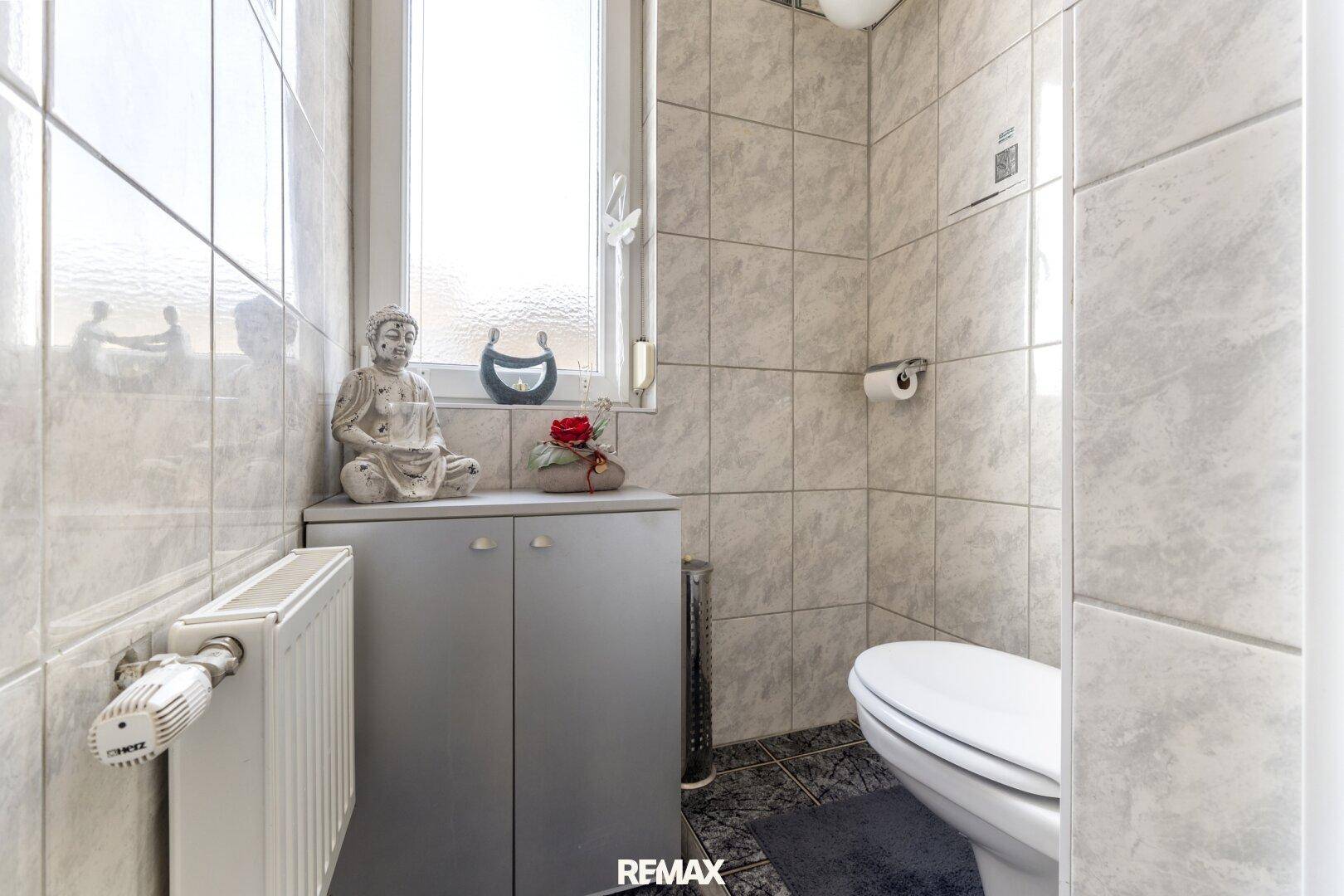 Kleines Gäste-WC mit Fenster, hellen Fliesen und Heizkörper.