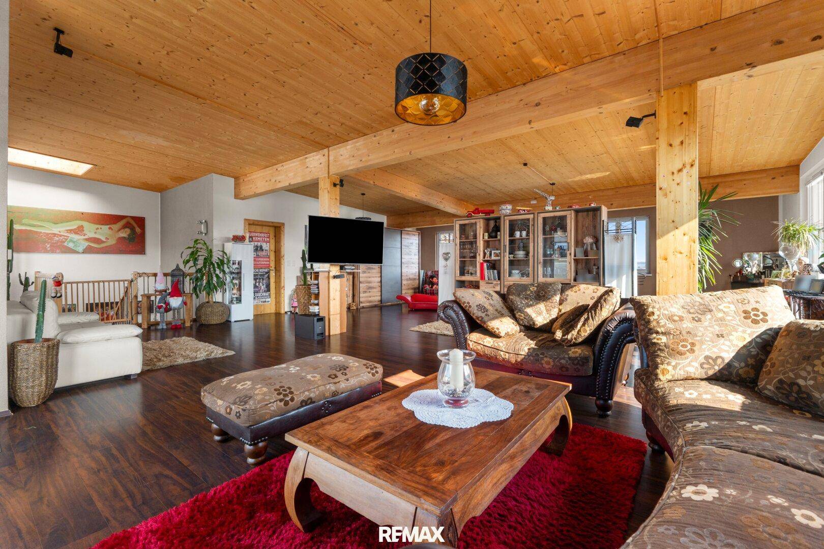 Großzügiger Wohnbereich mit Holzbalken, dunklem Holzboden und gemütlichen Sofas.