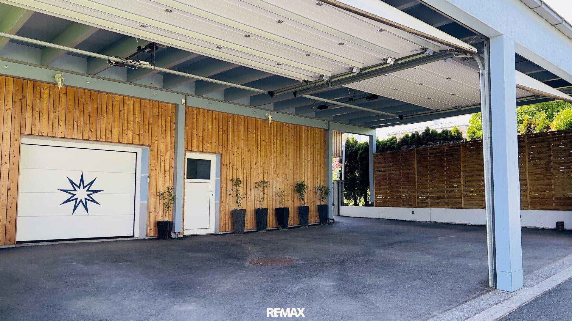 Überdachter Parkbereich mit Holzverkleidung und weiterer Garage.