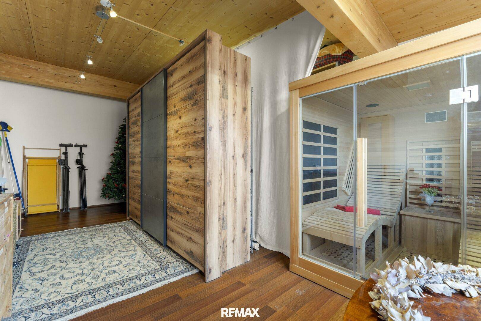 Bereich mit Holzschrank, Teppich und einer modernen Sauna.