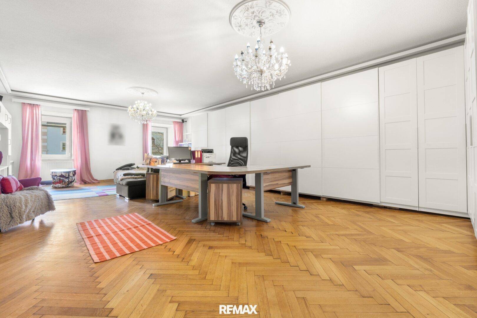 Geräumiges Büro mit Fischgrätparkett, großen Einbauschränken und eleganten Kronleuchtern.