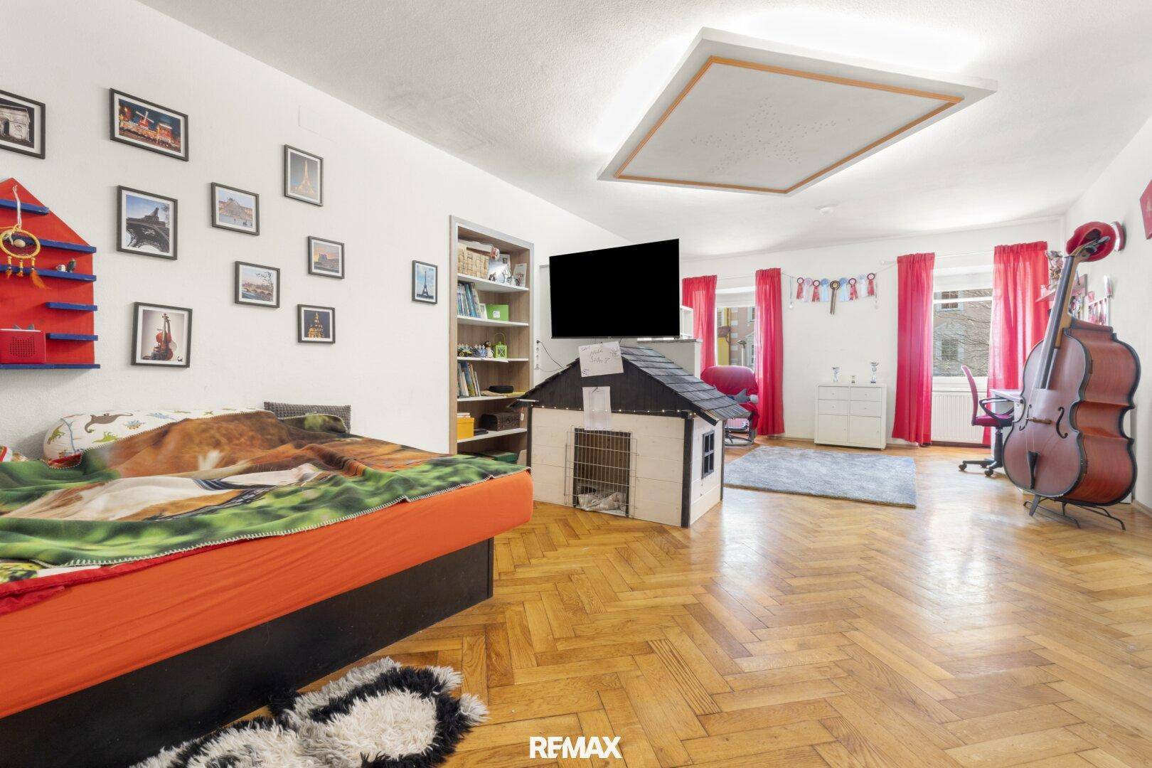 Geräumiges Kinderzimmer mit Bett, Fernseher und Spielzeug.