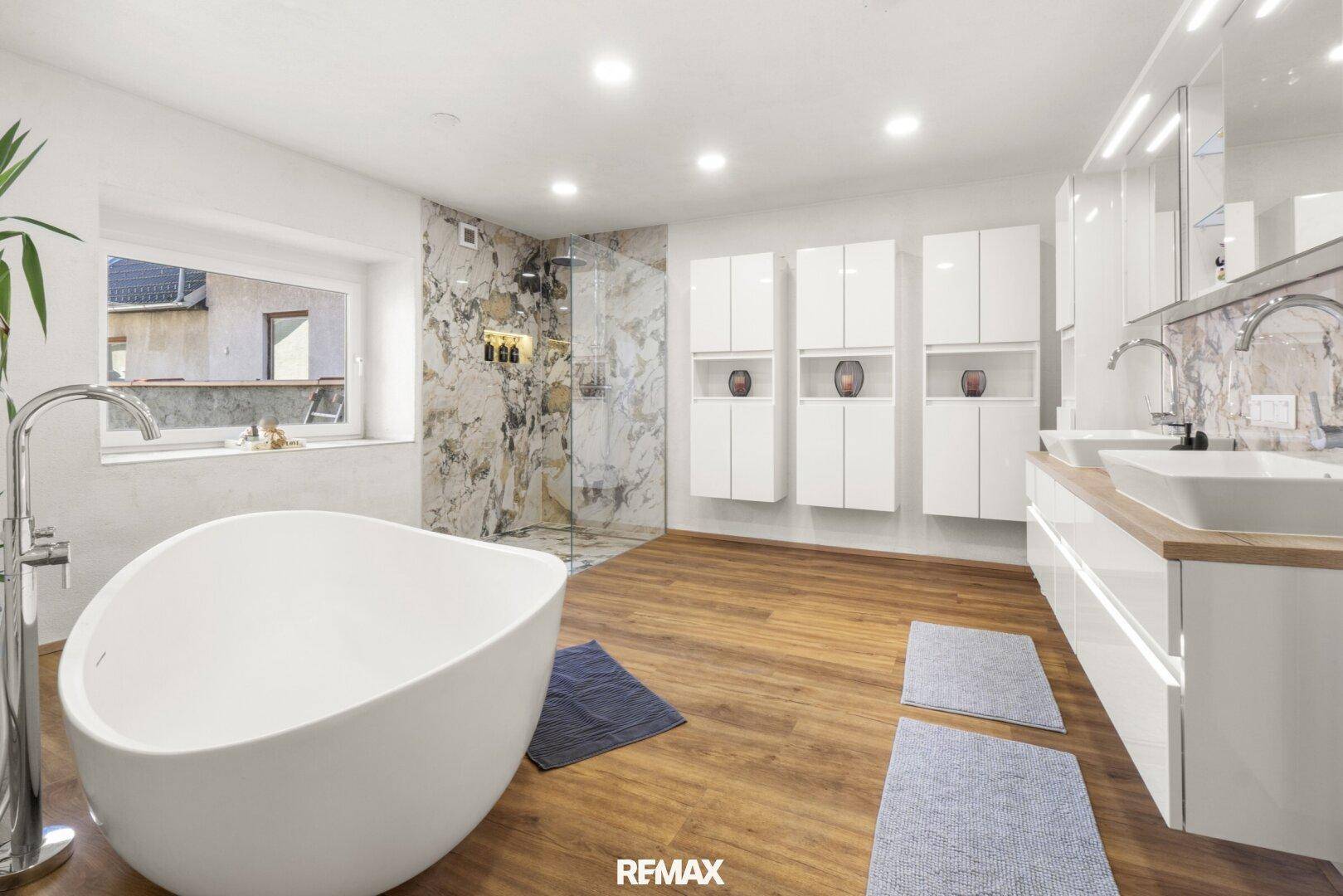 Luxuriöses Badezimmer mit freistehender Badewanne, Doppelwaschbecken und Marmorfliesen.