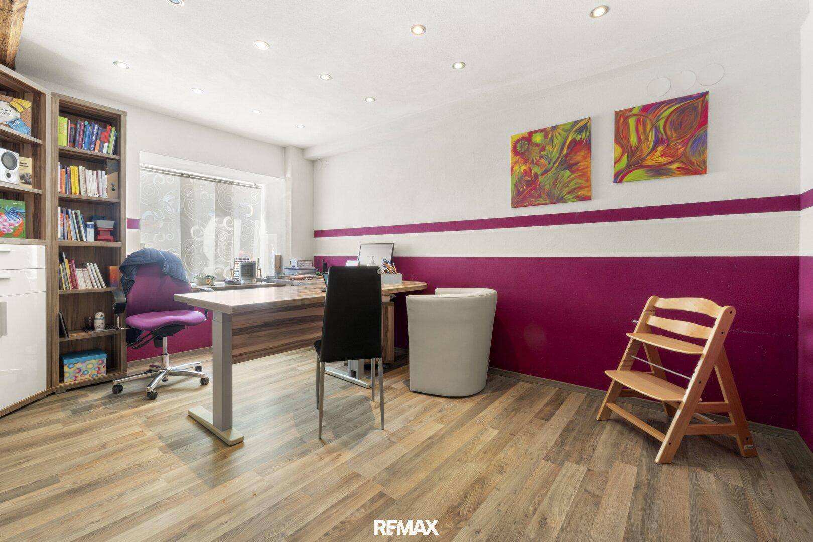 Helles Büro mit Holzfußboden, Bücherregal und farbigen Akzentwänden für eine inspirierende Arbeitsumgebung.