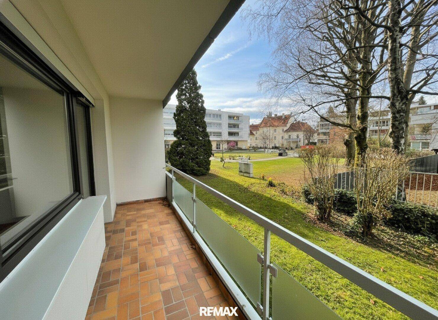 Heller Balkon mit Fliesenboden und Blick ins Grüne, ideal zum Entspannen im Freien.