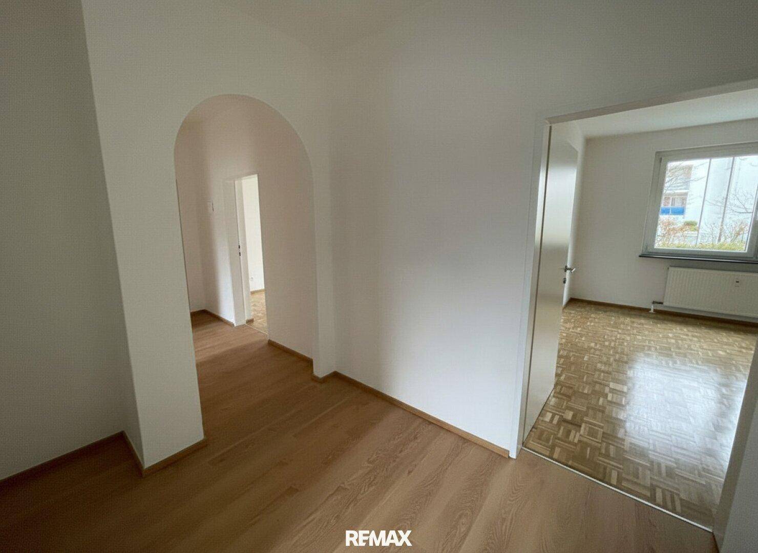 Heller Flur mit Laminatboden und einem Rundbogen, der zu weiteren Räumen führt.