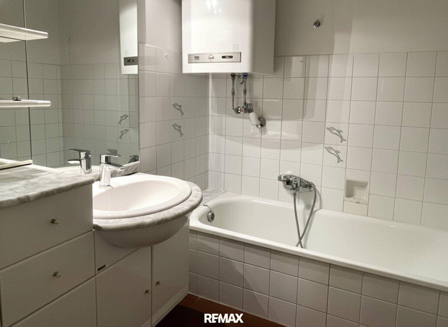 Badezimmer mit weiß gefliesten Wänden, Badewanne und Einzelwaschbecken.