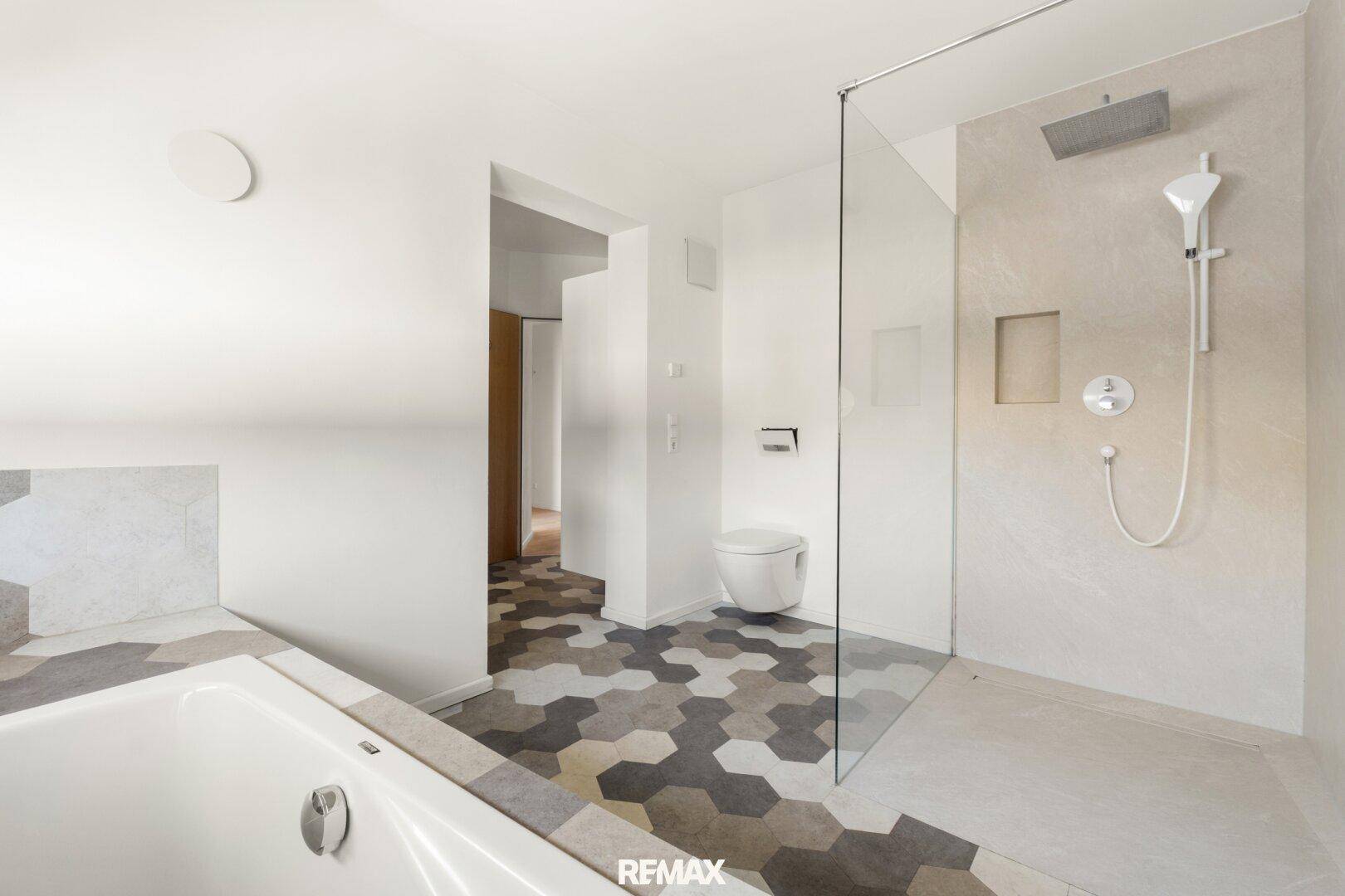 Modernes Badezimmer mit sechseckigen Fliesen, begehbarer Dusche und Badewanne.