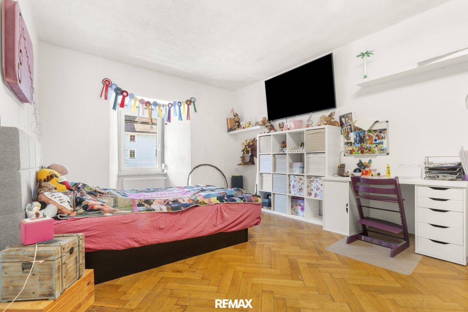 Kinderzimmer mit Einzelbett, Schreibtisch und bunten Dekorationen.