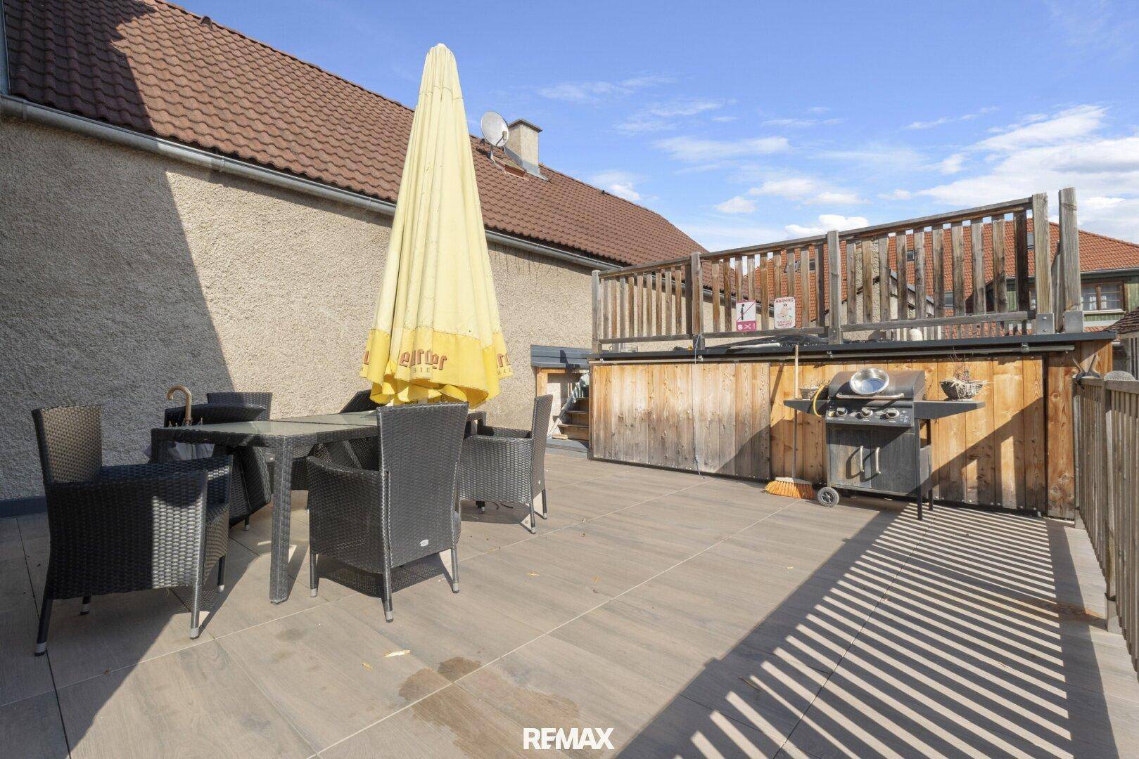 Große Dachterrasse mit Essbereich, Grill und Holzgeländer.