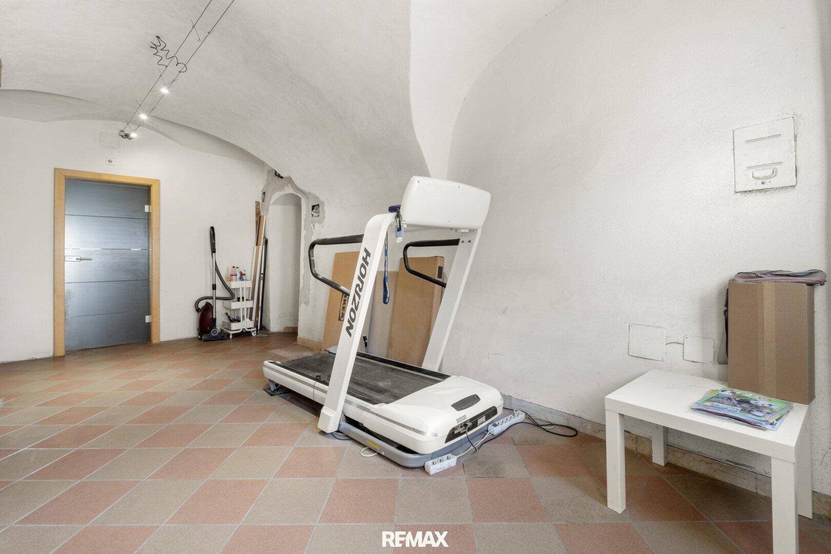 Fitnessraum mit Laufband, Terrakottafliesen und charakteristischer Gewölbedecke im Untergeschoss.