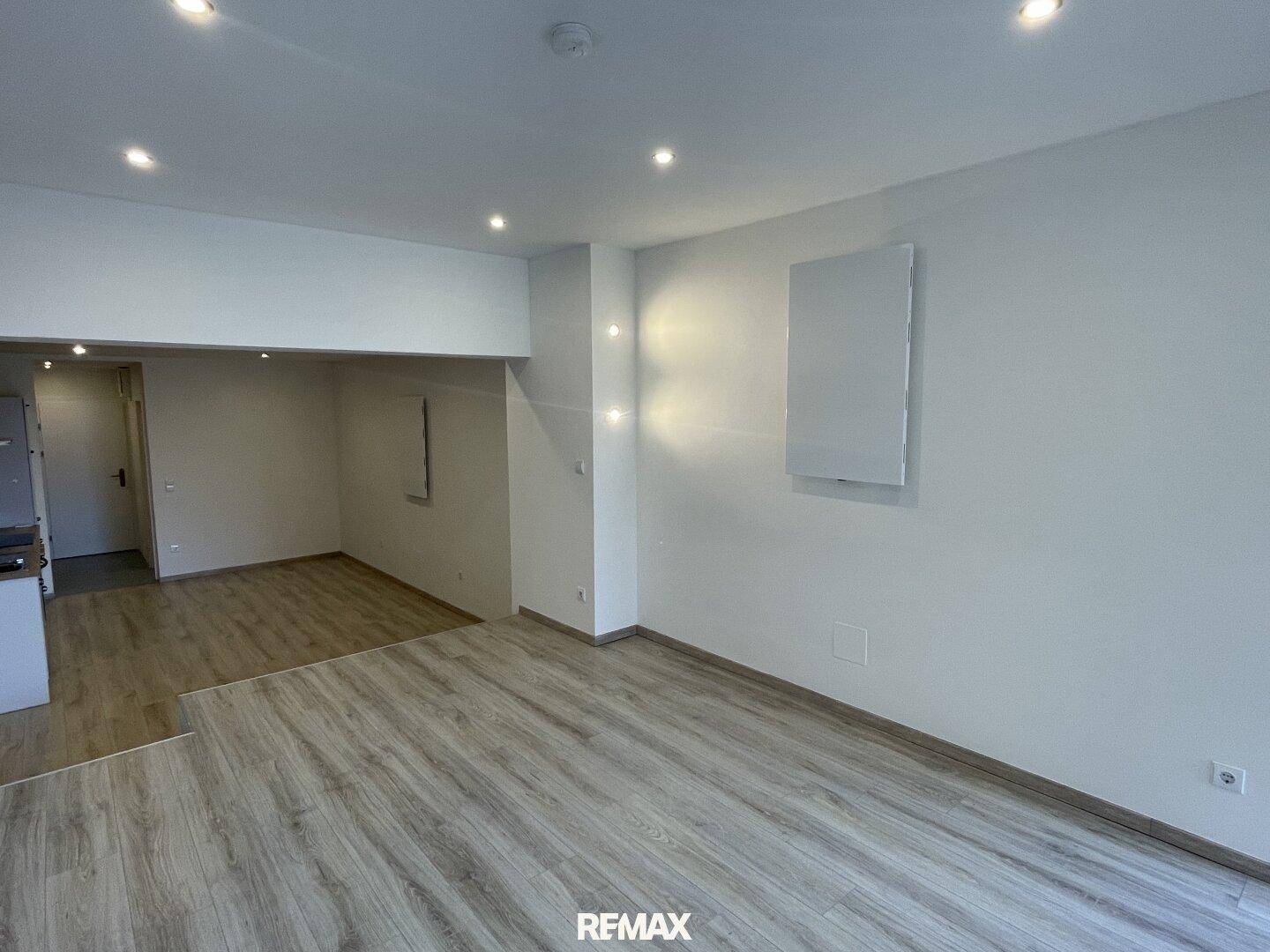 Geräumiger Innenraum mit hellem Laminatboden und moderner Beleuchtung, bereit zur individuellen Gestaltung.