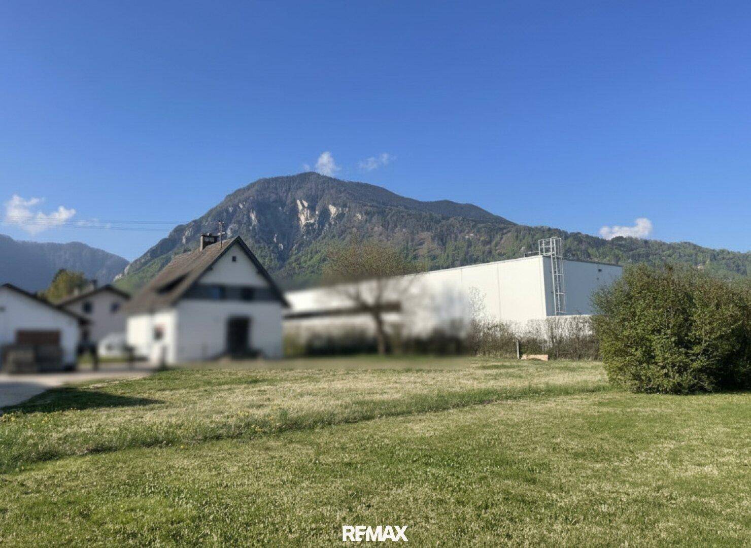 Weitläufiges Gelände mit Bergblick und umliegender Bebauung unter klarem blauem Himmel.