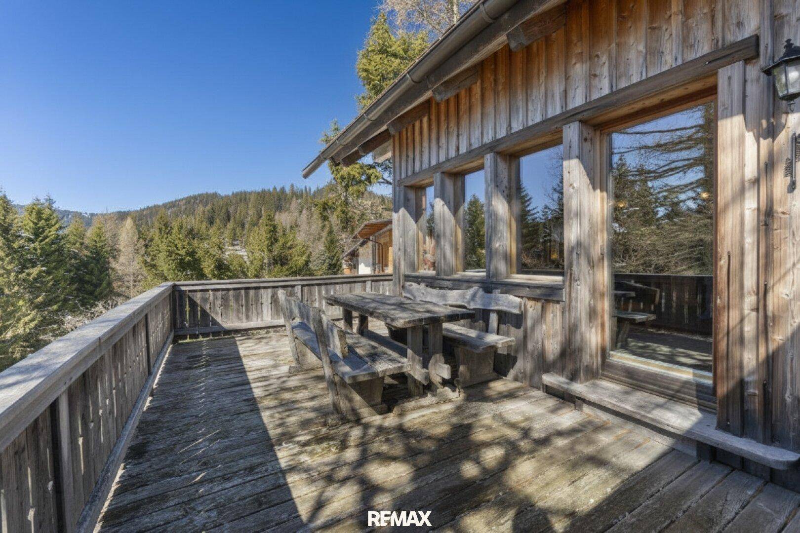 Große Holzterrasse mit rustikalen Sitzgelegenheiten und weitem Blick auf die umliegende Berglandschaft.