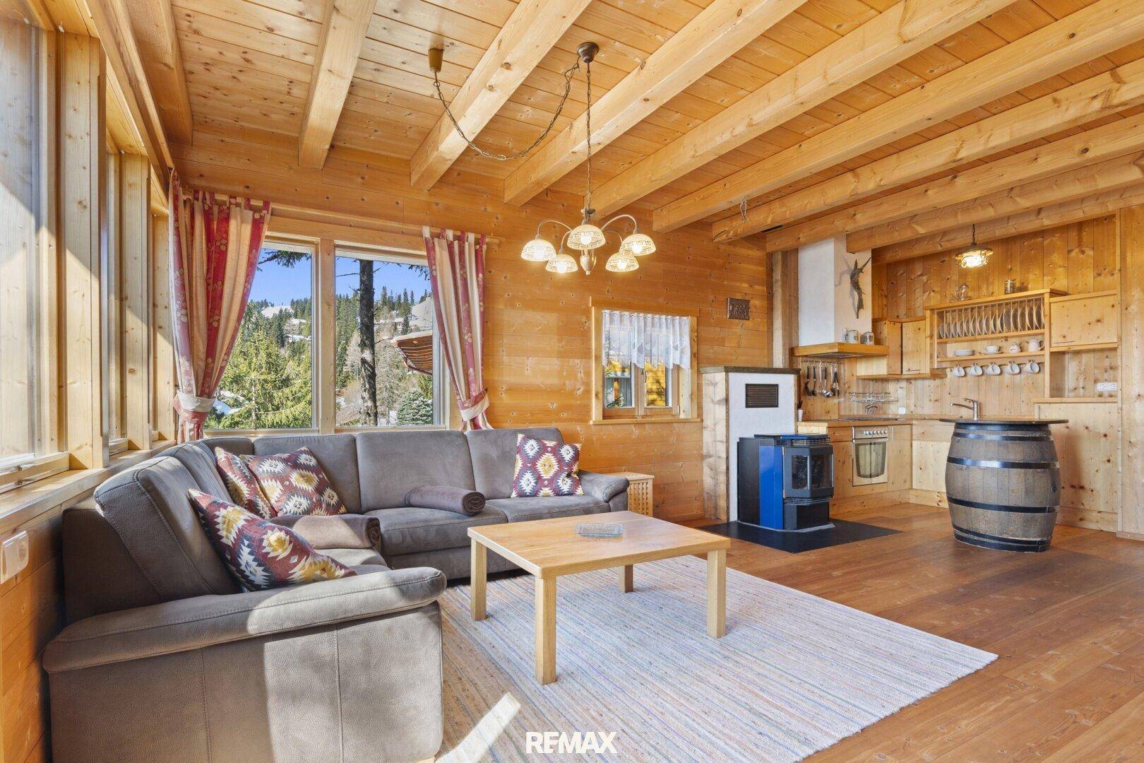 Offener Wohnbereich mit Holzbalkendecke, integrierter Küchenzeile und traditionellem Holzofen.