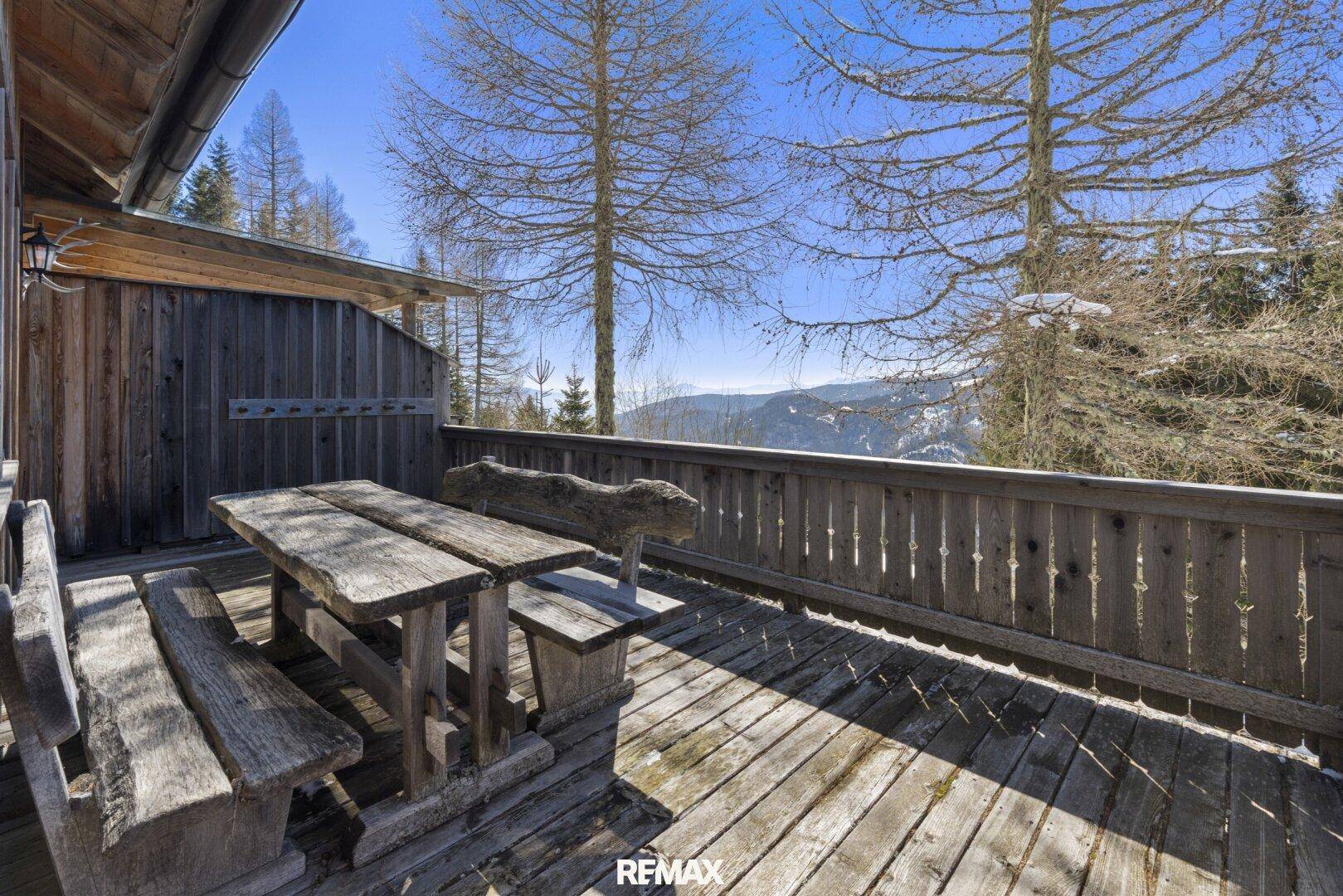Rustikale Holzterrasse mit Sitzgelegenheiten und weitem Blick auf die verschneite Berglandschaft.
