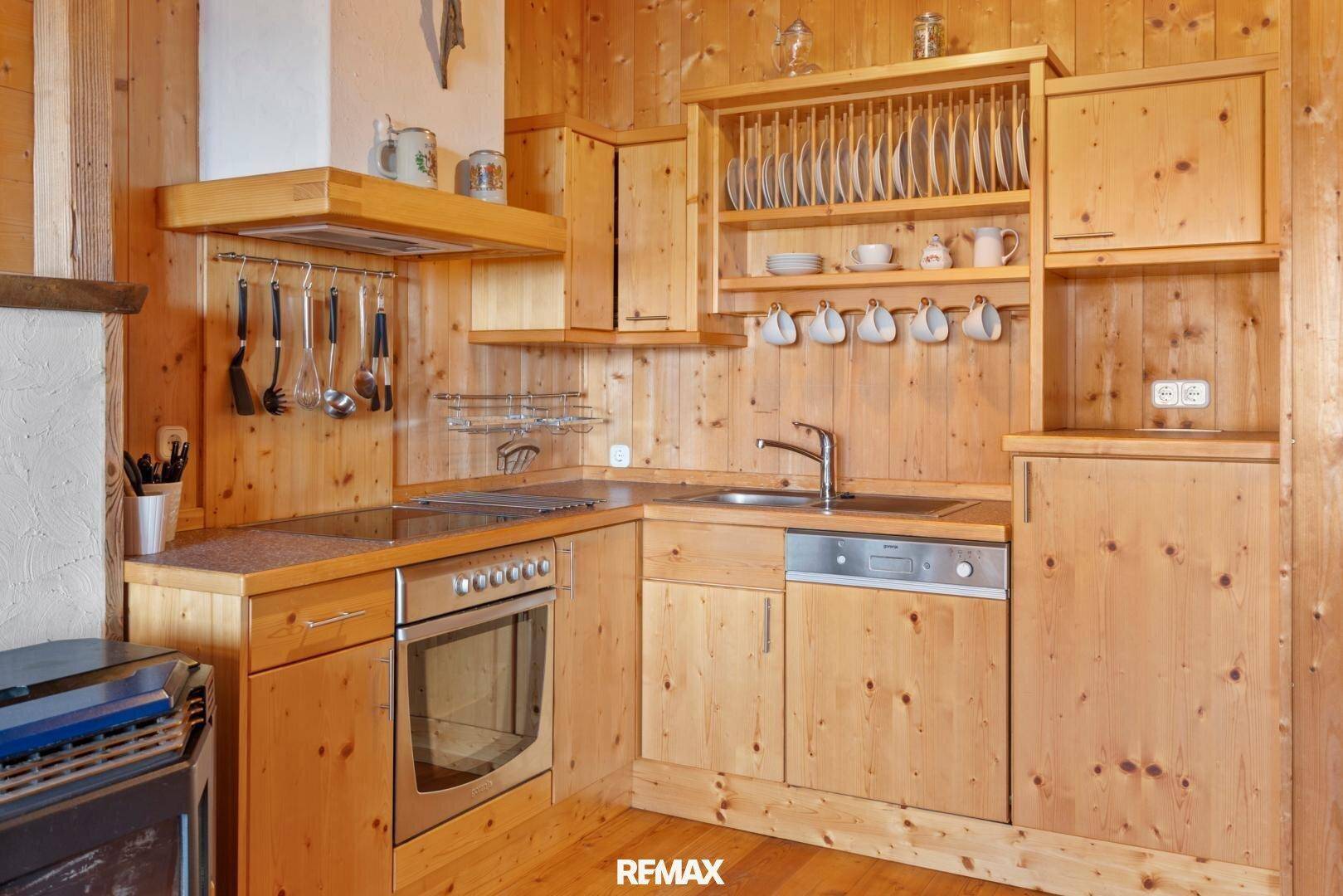 Funktionale Küche im rustikalen Stil mit Holzeinbauten, Herd, Spüle und Geschirrspüler.