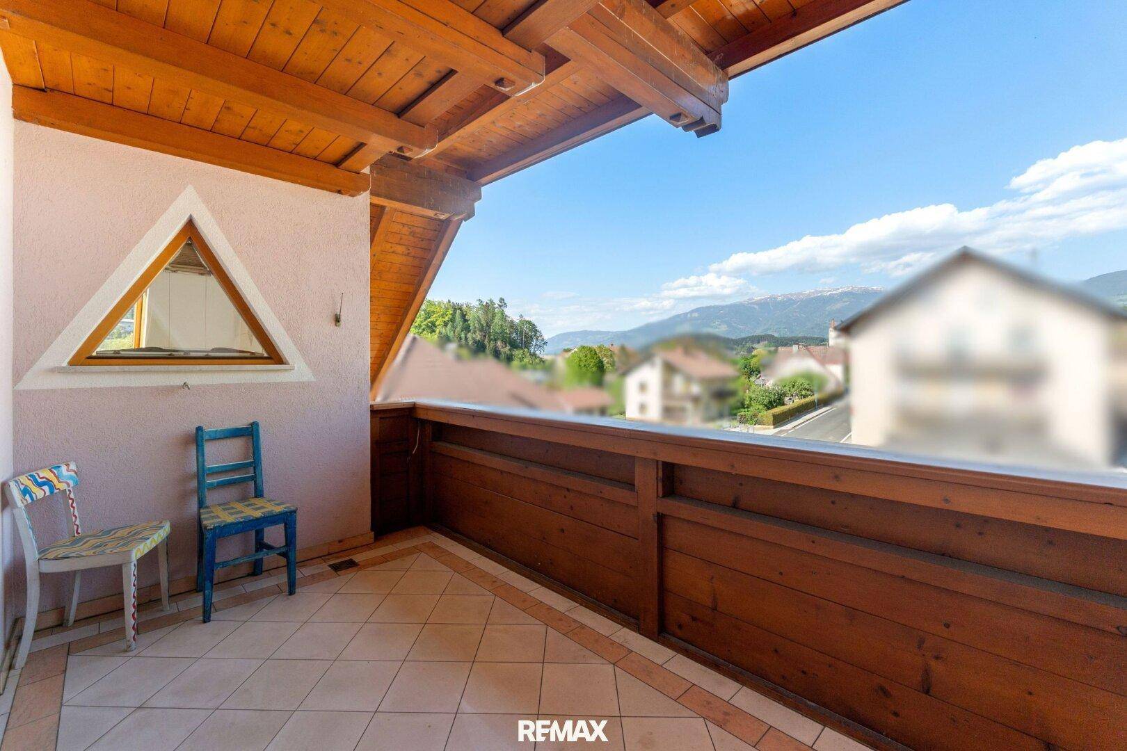 Gemütlicher Balkon mit Holzelementen und Fliesenboden, bietet einen weiten Blick auf die Berge.