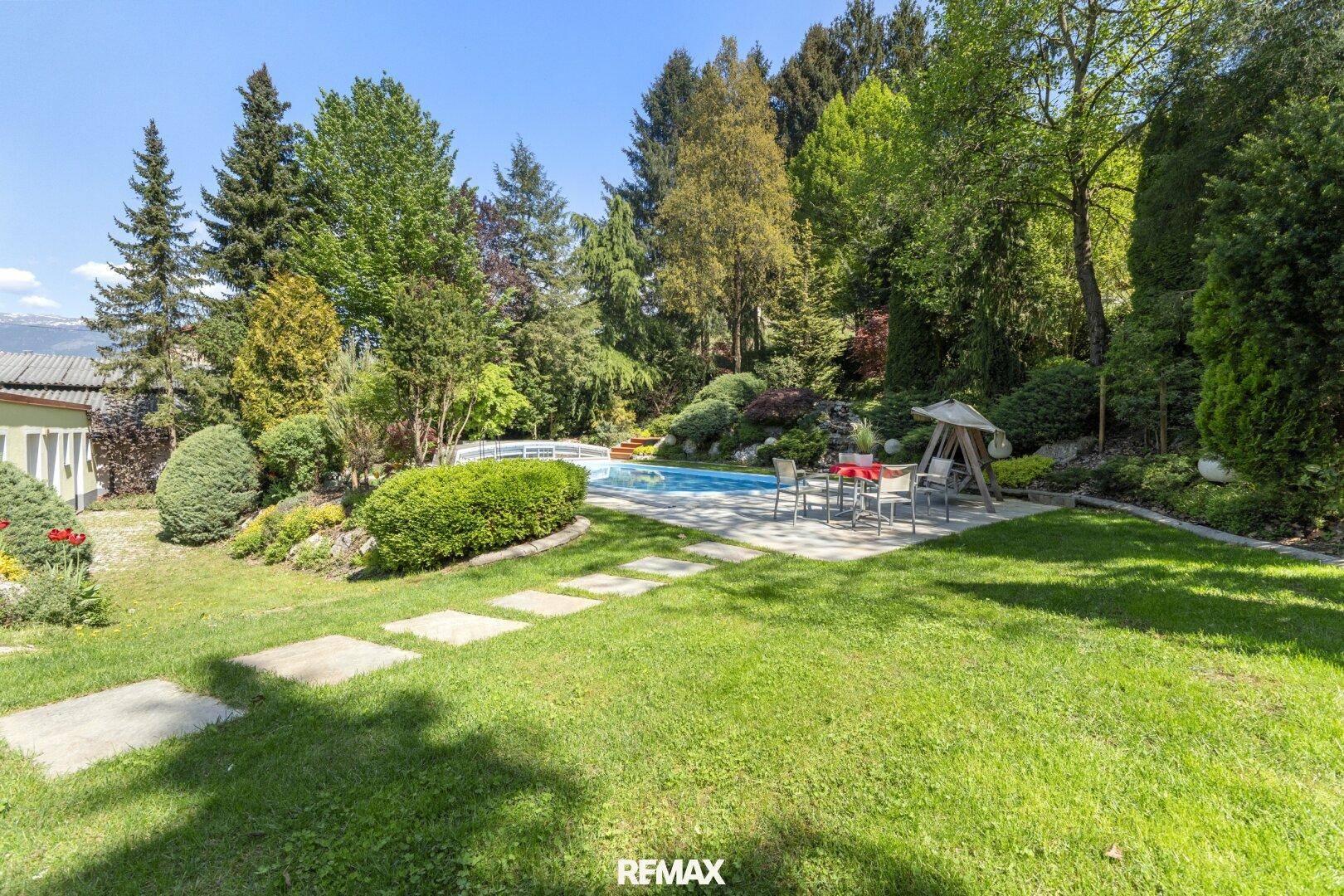 Großer, gepflegter Garten mit Swimmingpool, Rasenfläche und Sitzgelegenheiten im Freien.