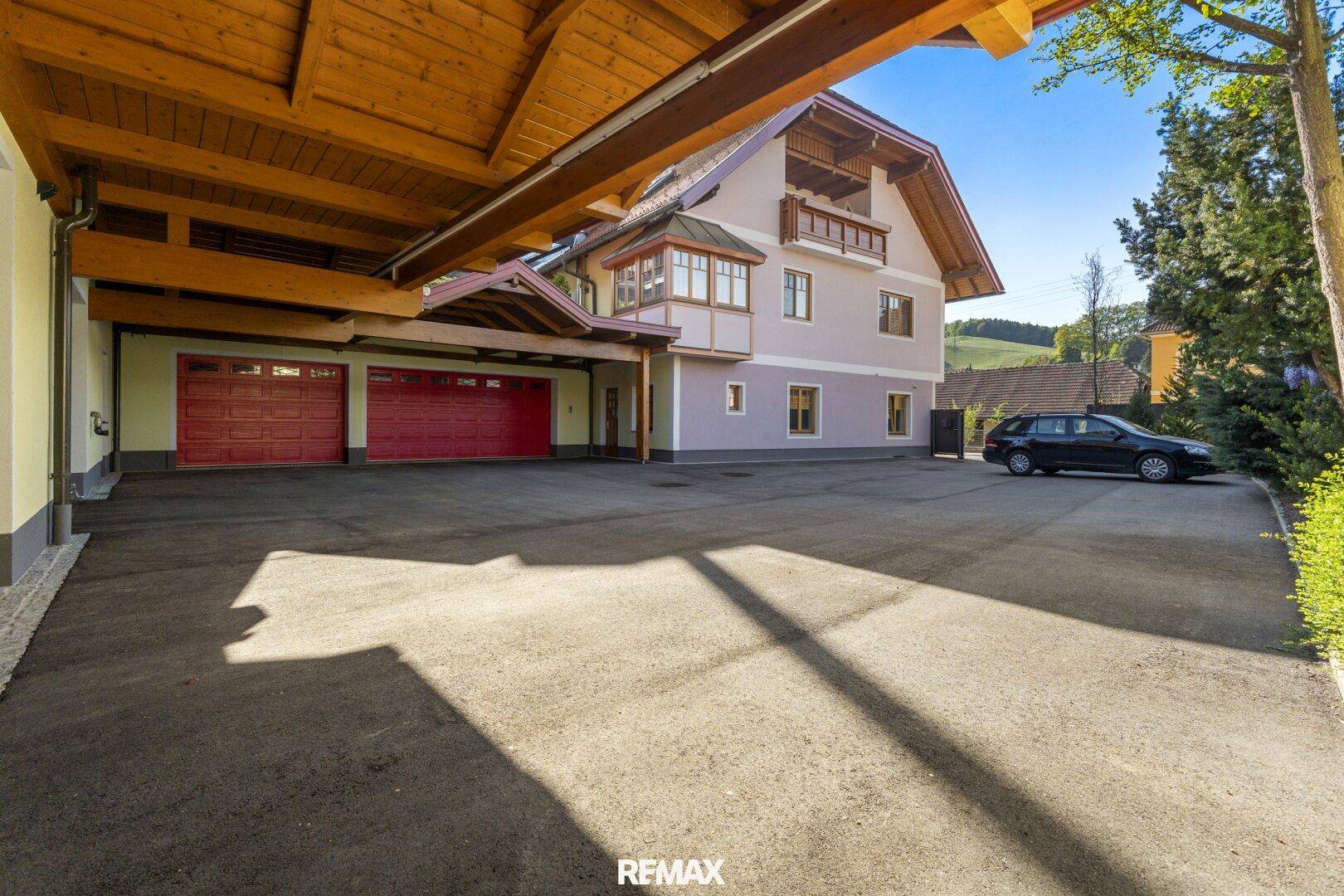 Großzügige Zufahrt mit Carport und mehreren Garagentoren vor dem Wohnhaus.