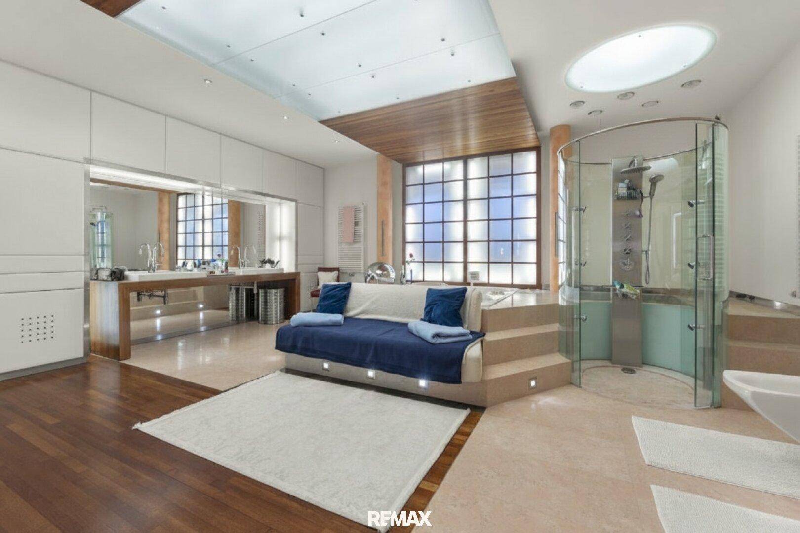 Luxuriöses Badezimmer mit großer Duschkabine, Doppelwaschbecken und Sitzbereich.