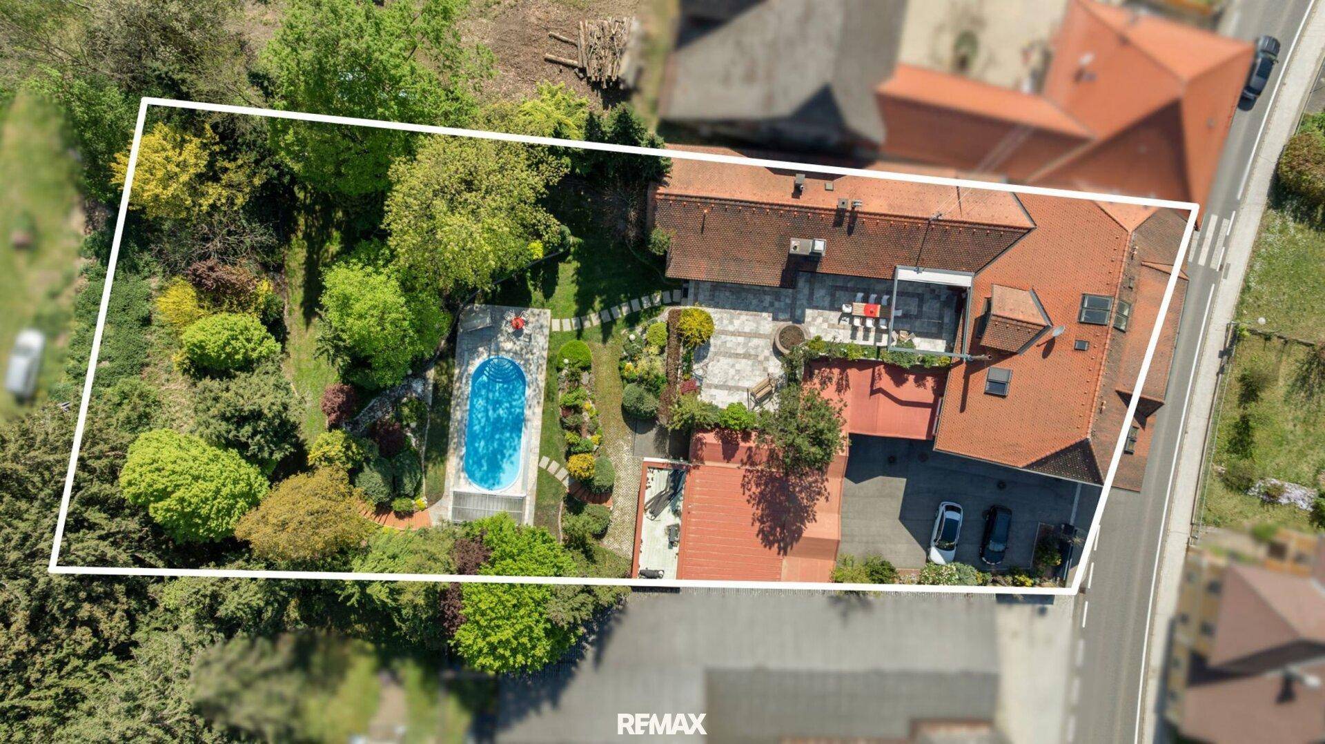 Luftaufnahme des Anwesens mit Pool, Garten und Wohnhaus, umrandet von einer weißen Linie.