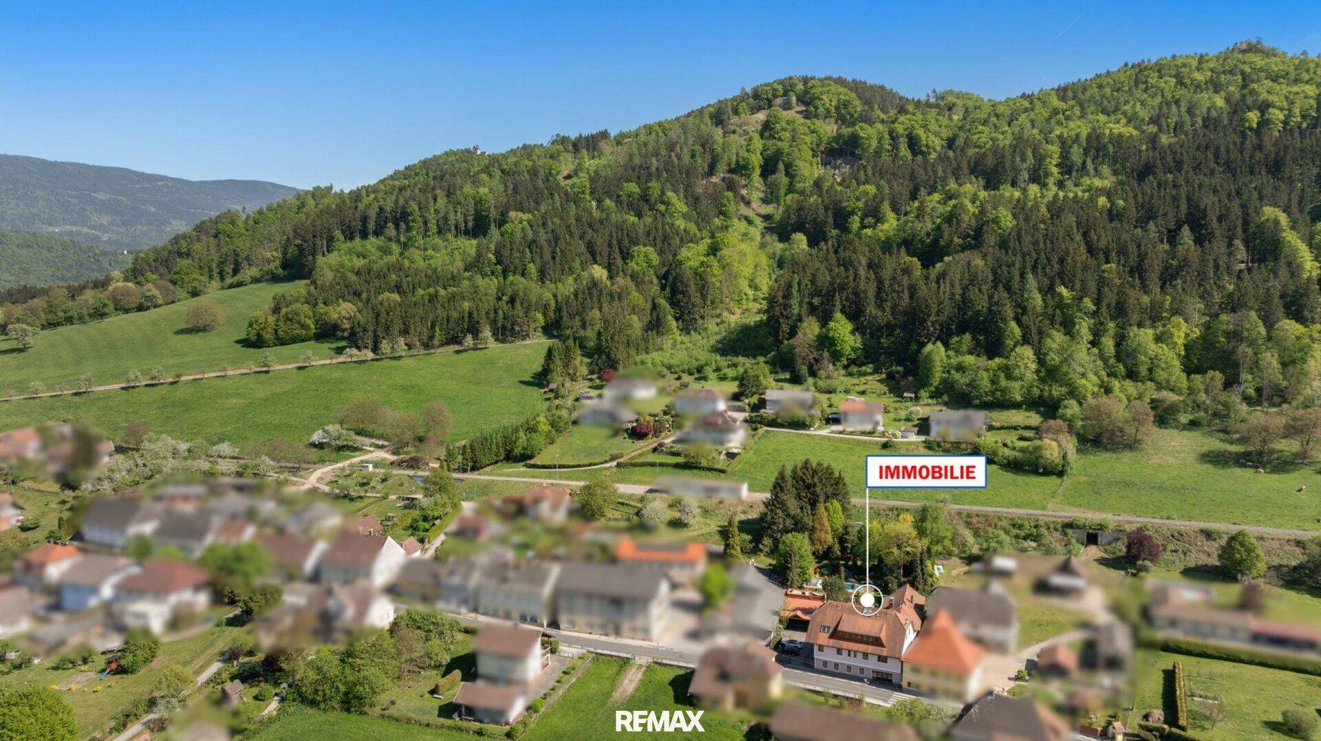 Luftaufnahme der Immobilie in ländlicher Umgebung mit grünen Hügeln und Wäldern im Hintergrund.