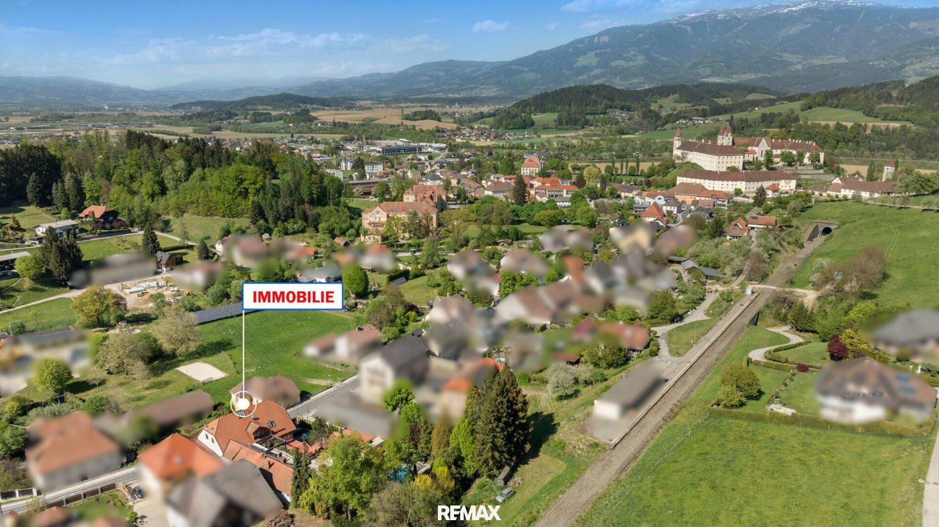 Weitläufige Luftaufnahme der Immobilie und der umliegenden Ortschaft mit Bergen am Horizont.