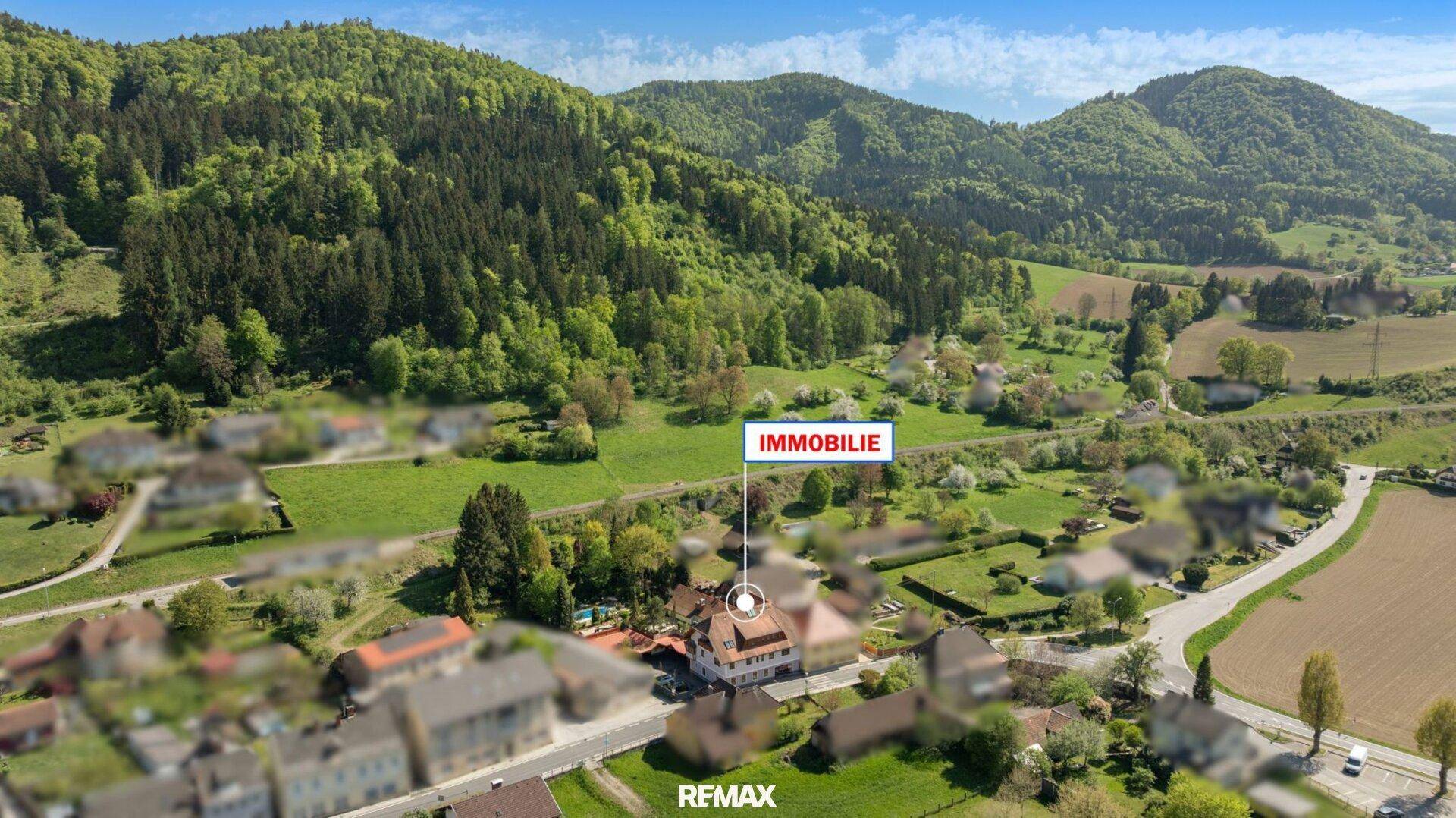 Panoramische Luftaufnahme der Immobilie eingebettet in eine grüne, hügelige Landschaft.