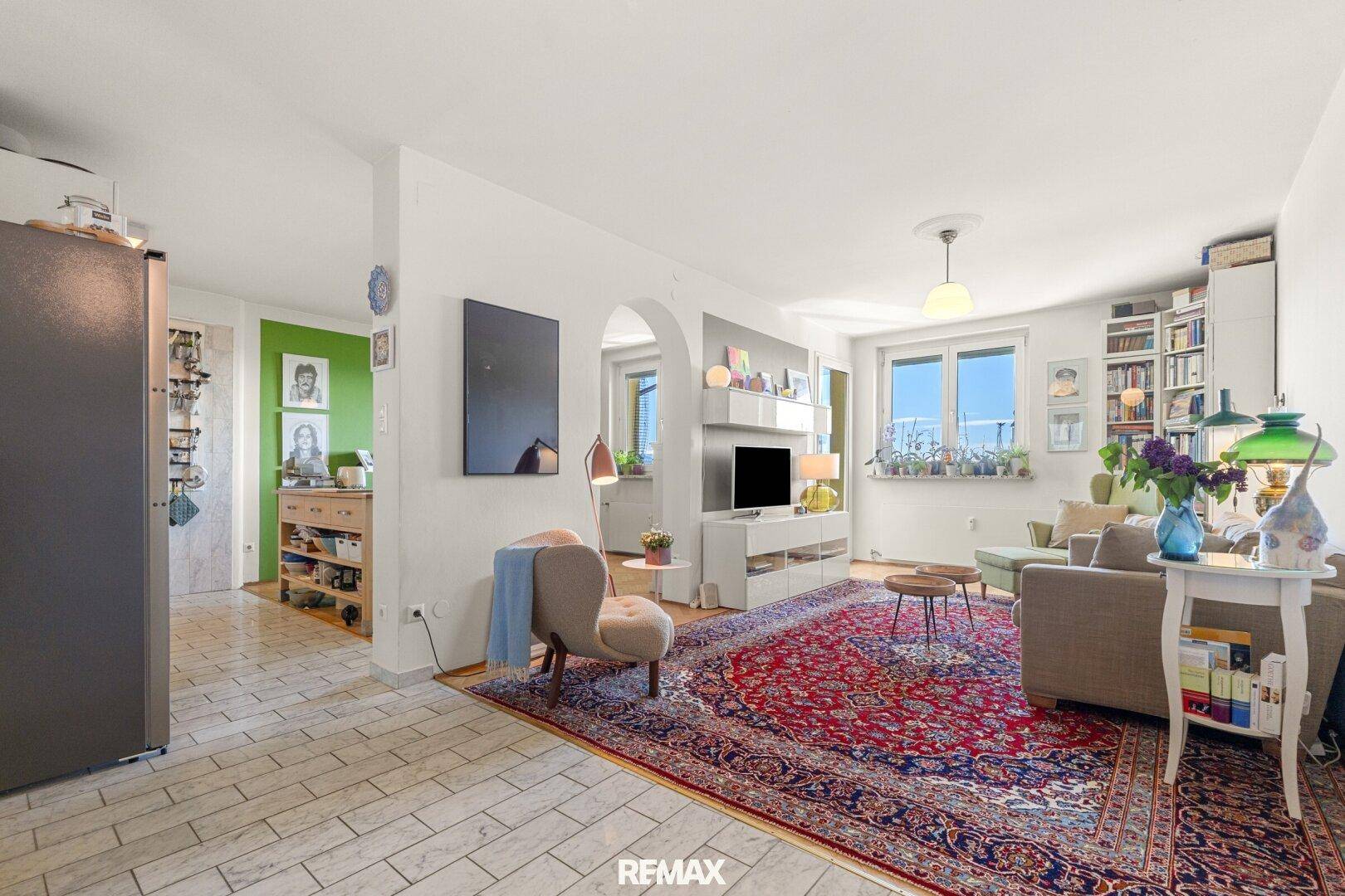 Helles Wohnzimmer mit Teppichboden, bequemen Sofas und Blick in die angrenzende Küche.