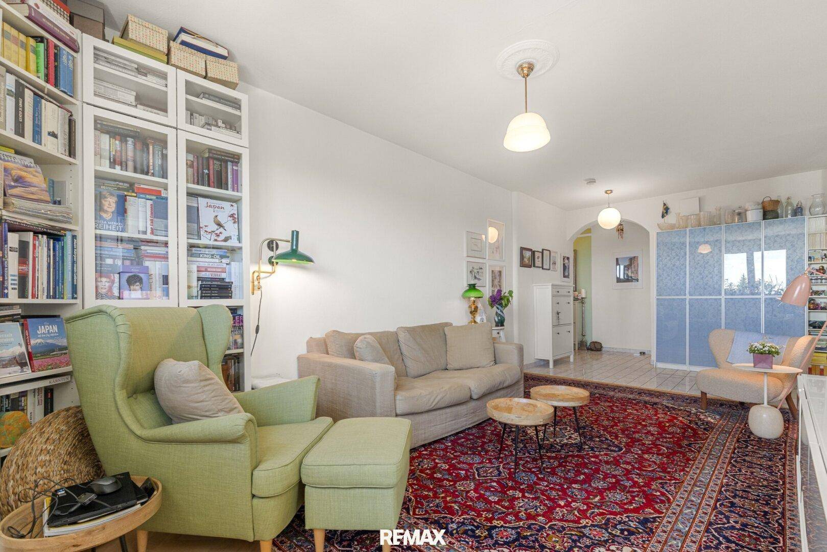 Helles Wohnzimmer mit gemütlicher Sitzecke, Bücherregalen und einem traditionellen Teppich, der den Raum schmückt.